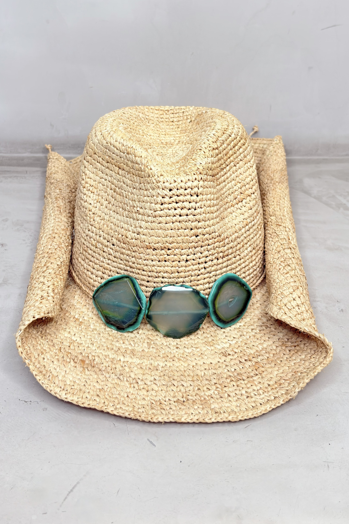 Sombrero de rafia artesanal color natural con ala ancha y detalle de piedras verdes en la banda frontal
