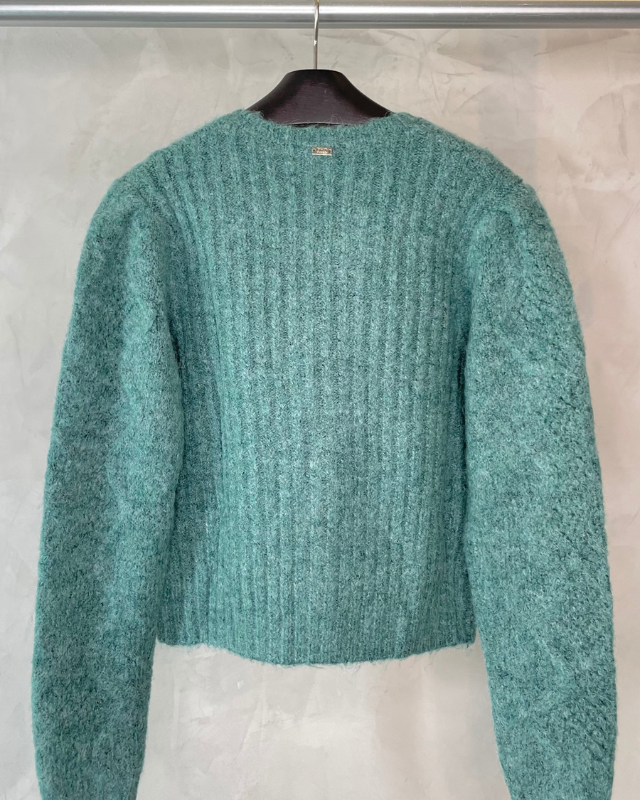 Vista trasera del cardigan Pho Firenze en color verde bosque colgado en percha, mostrando el acabado y detalles del tejido de lana merino
