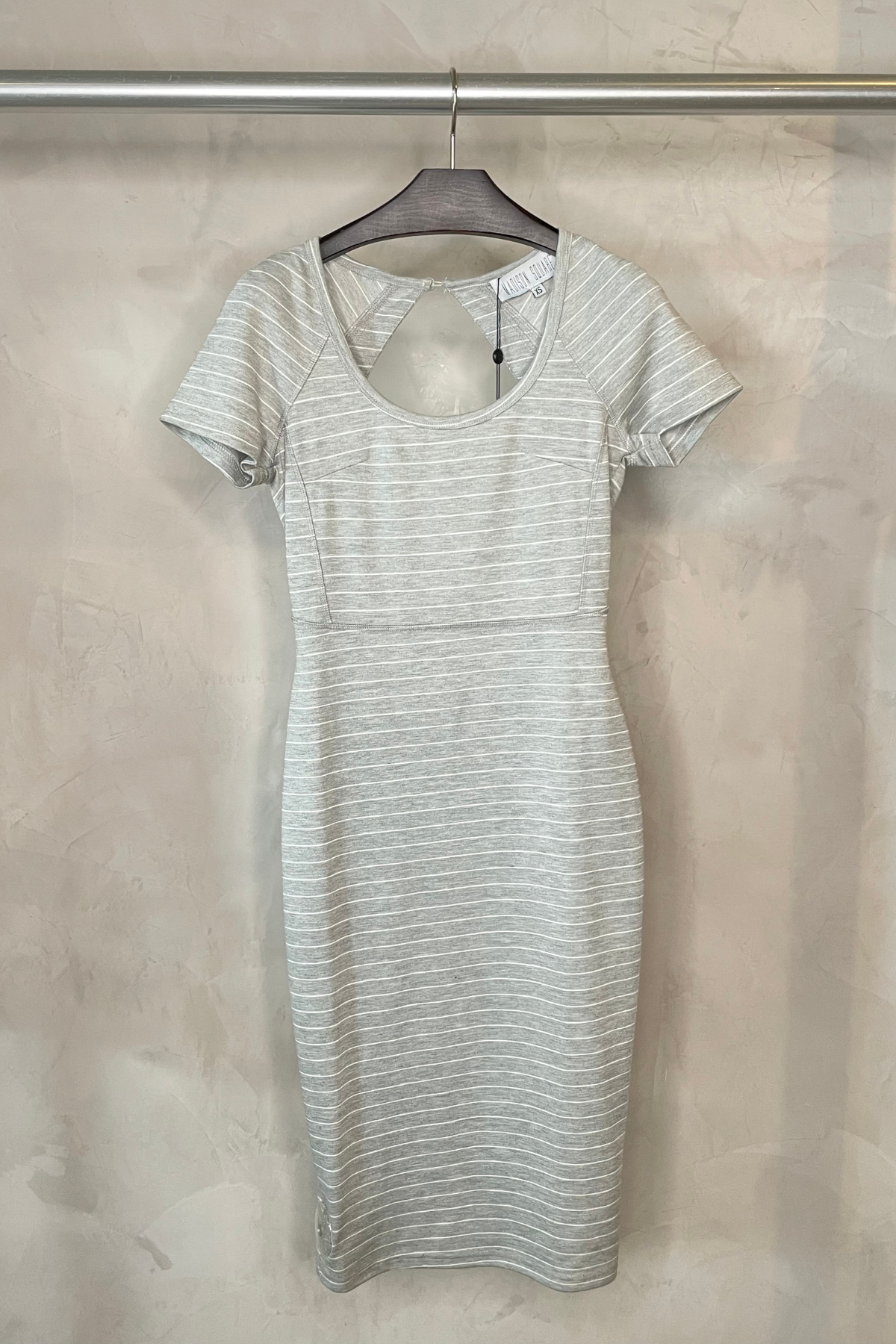 Vestido midi Madison Square Meet Me colgado en percha con diseño negro elegante y detalles estructurados sobre fondo blanco limpio