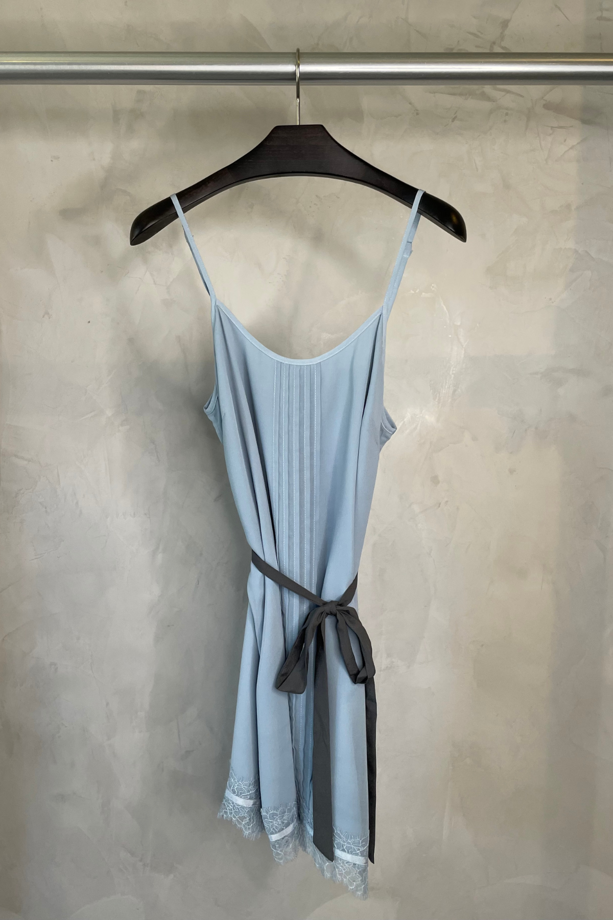 Vestido mini Elia de Wink colgado en percha sobre fondo neutro, destacando el color azul cielo y detalles del tejido