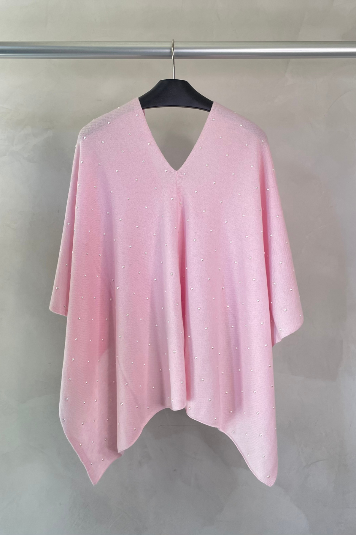 Poncho rosa sobre percha, tejido de cashmere y merino suave y caída fluida perfecta para estilismos de entretiempo