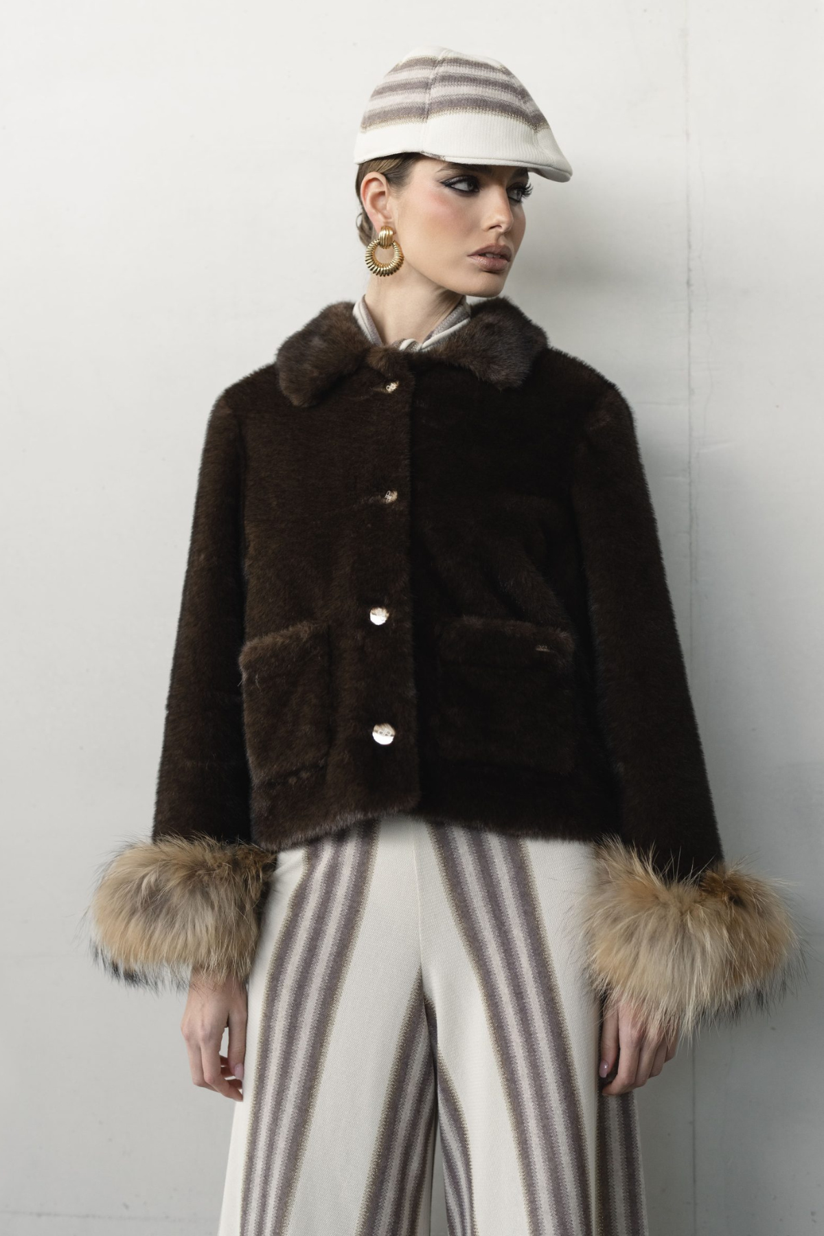 Modelo con chaqueta de piel sintética negra Pho Firenze y pantalones de rayas para conjunto elegante de invierno