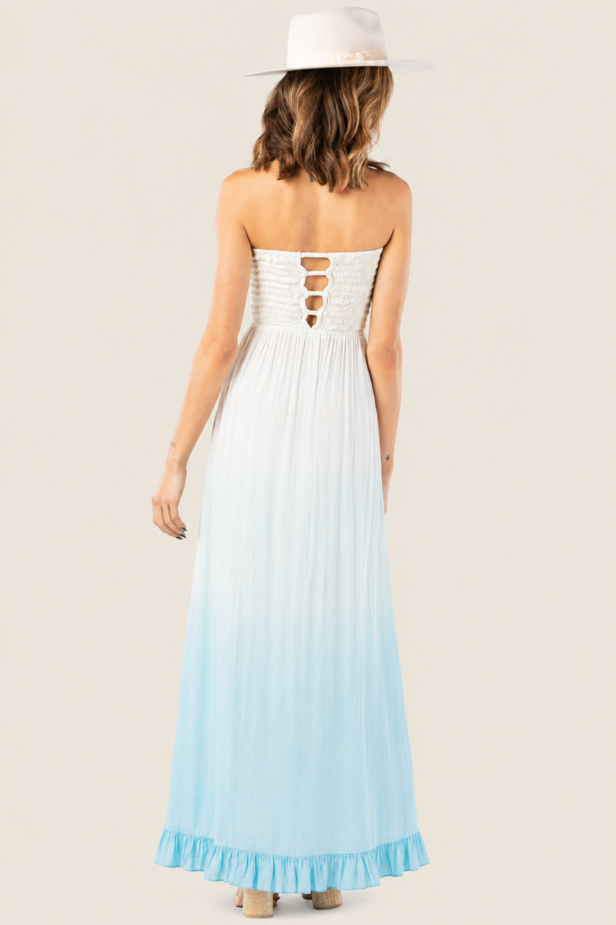 Vista trasera del Flynn maxi dress degradado crema‑teal‑blue en maniquí, con detalle de cut‑out en espalda y caída fluida