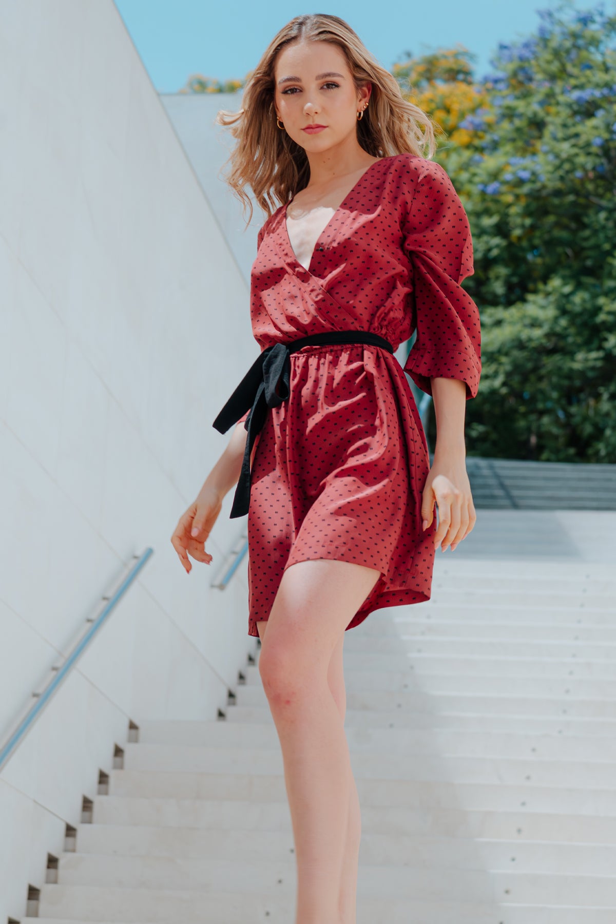 Modelo posando frontalmente con vestido corto Eskell Eva en rust, estampado minimalista, mangas ¾ y escote en V sobre fondo neutro