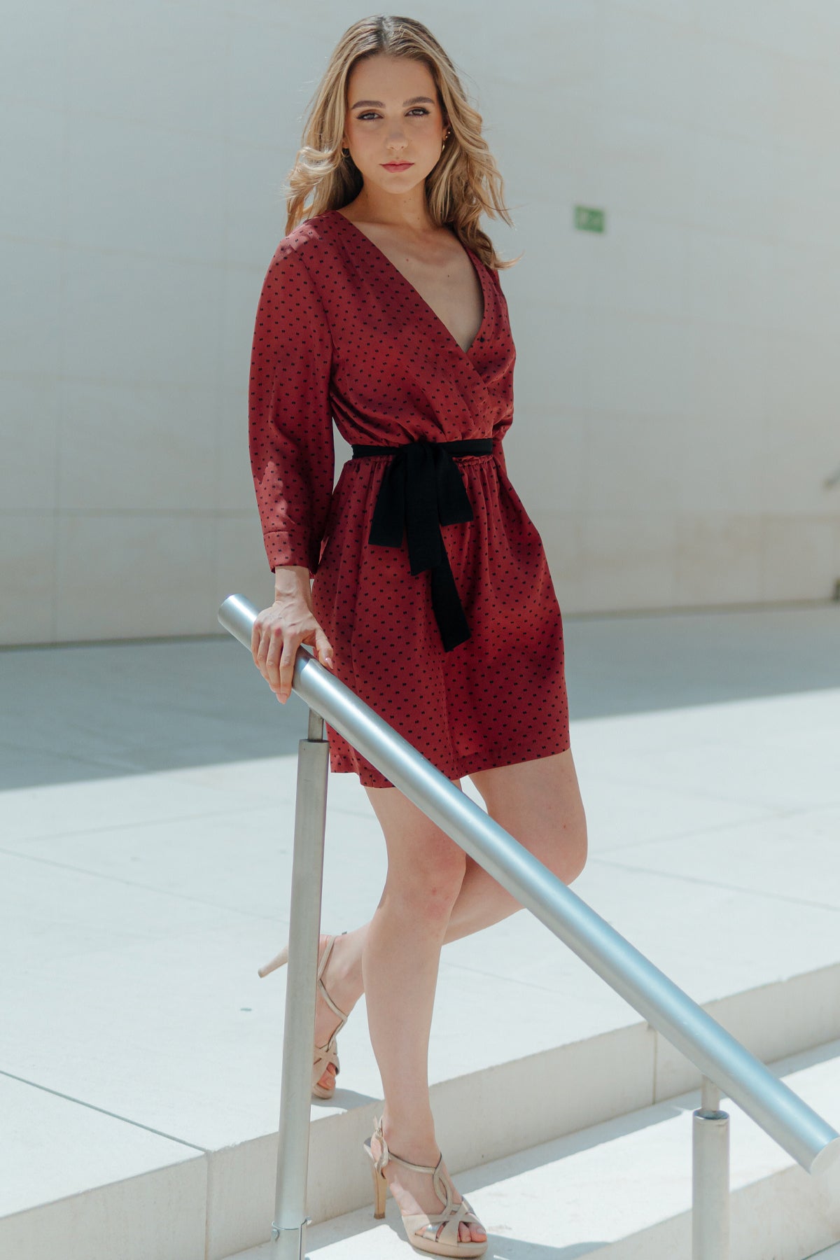 Modelo posando con vestido corto Eskell Eva en rust, escote en V y mangas ¾, destacando la caída fluida sobre fondo neutro