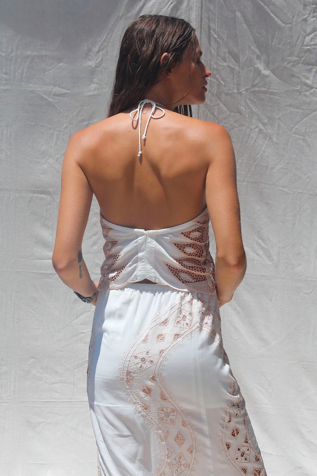 Modelo de espaldas con el Dolly Crop Top en color Western Bone mostrando el diseño halter anudado y cierre trasero discreto