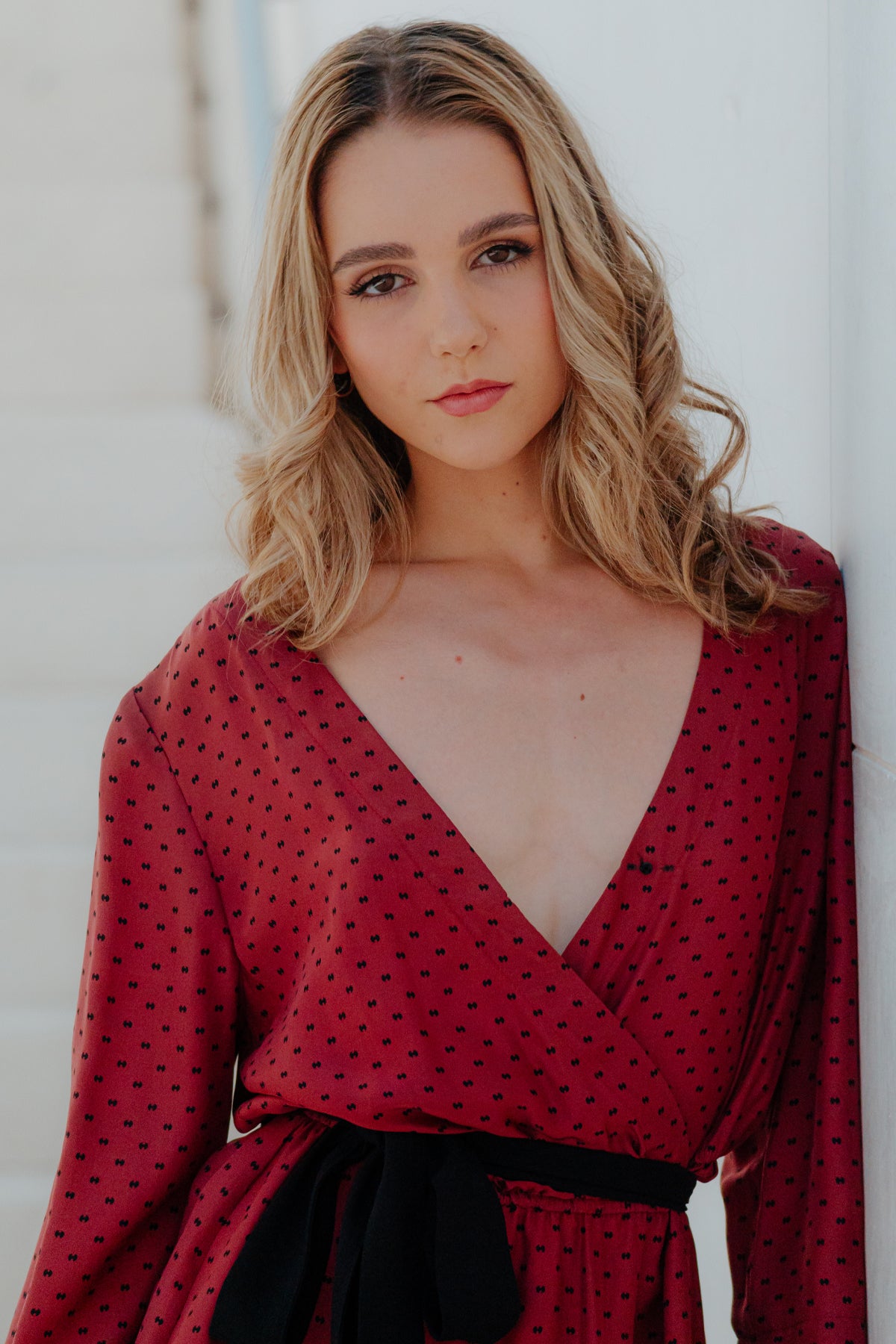 Primer plano del escote en V y botón clip del vestido Eskell Eva, resaltando cuello envolvente y textura de seda en color rust