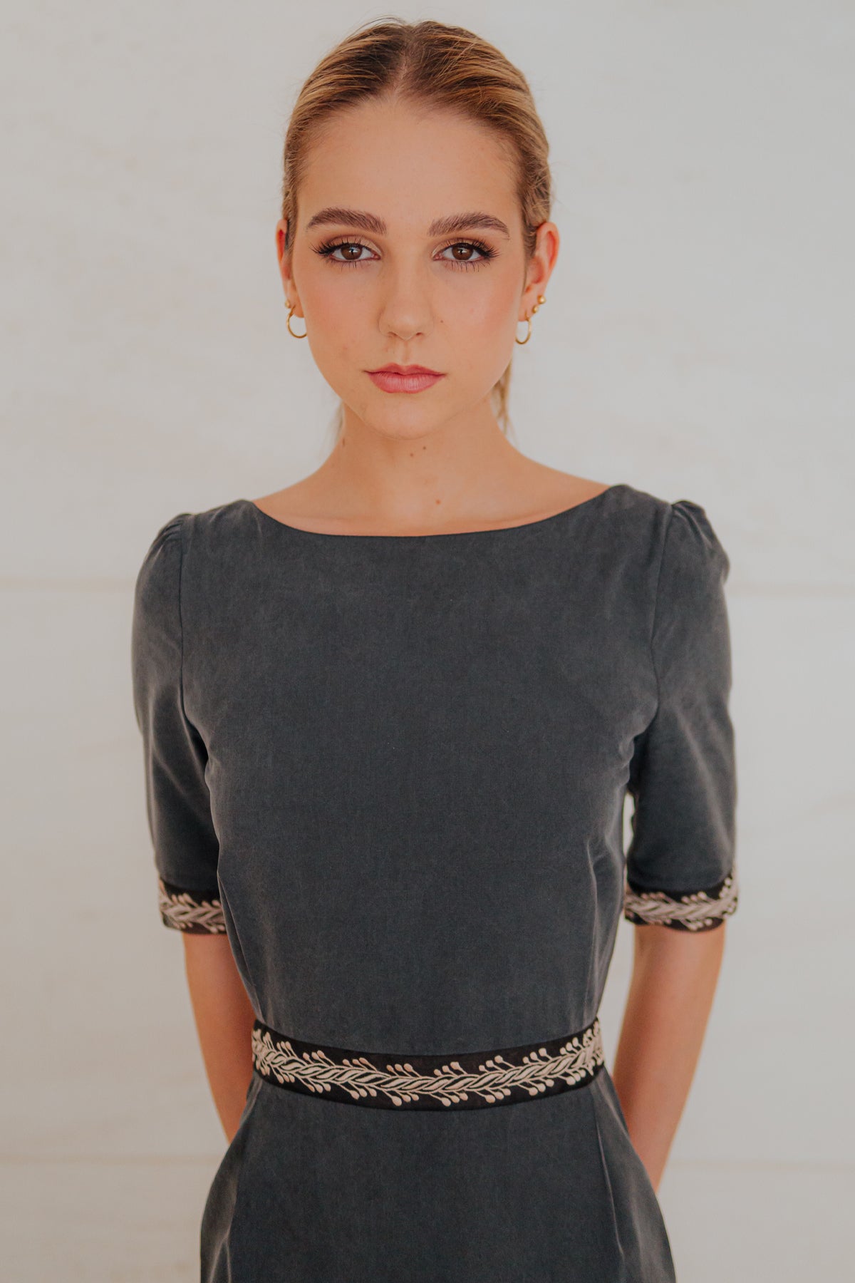 Modelo posando con vestido midi Mike de Lyell en gris sobre fondo blanco, mostrando elegancia y estilo contemporáneo