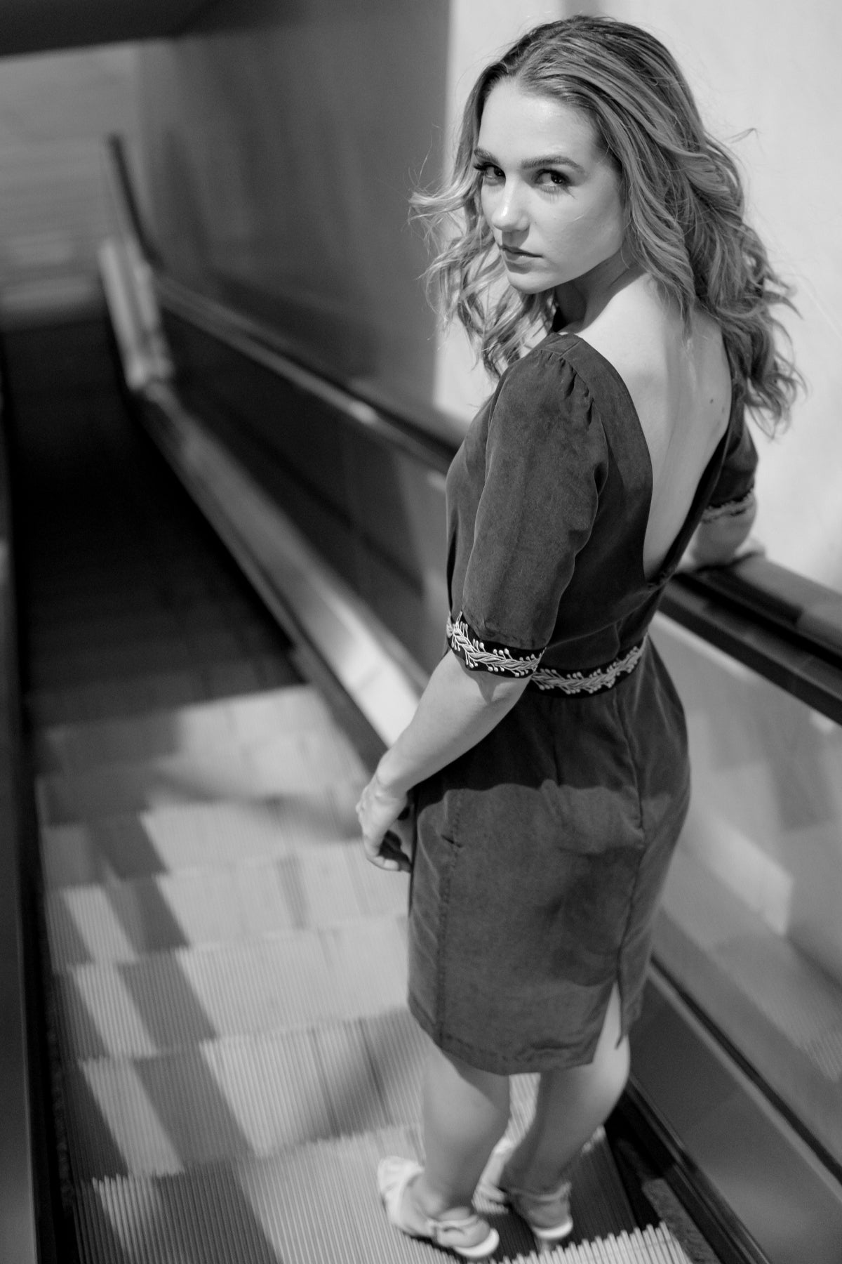 Fotografía en blanco y negro de la modelo con vestido midi Mike de Lyell en gris en plano trasero, resaltando líneas y silueta elegante