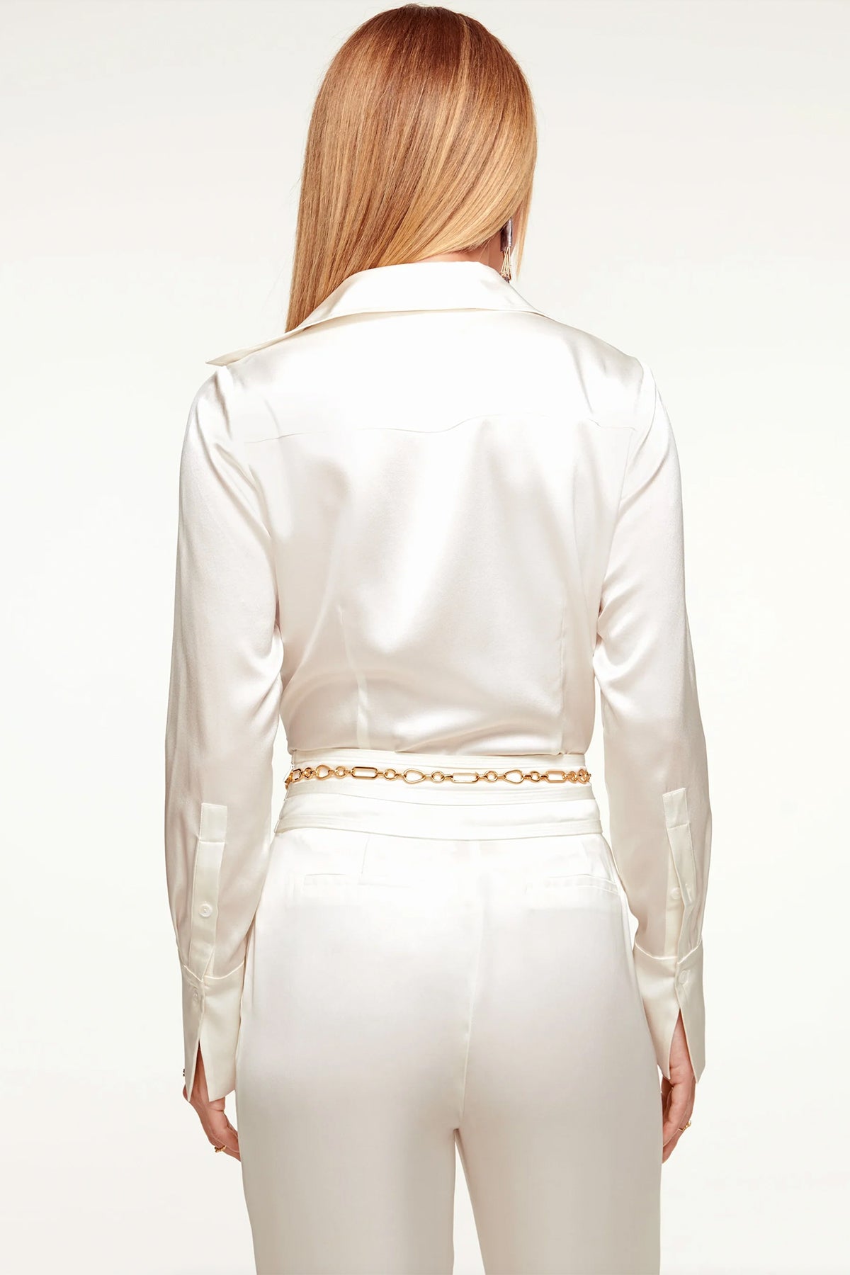 Espalda con drapeado sutil y etiqueta bordada, destacando la caída fluida de la seda marfil en movimientos naturales