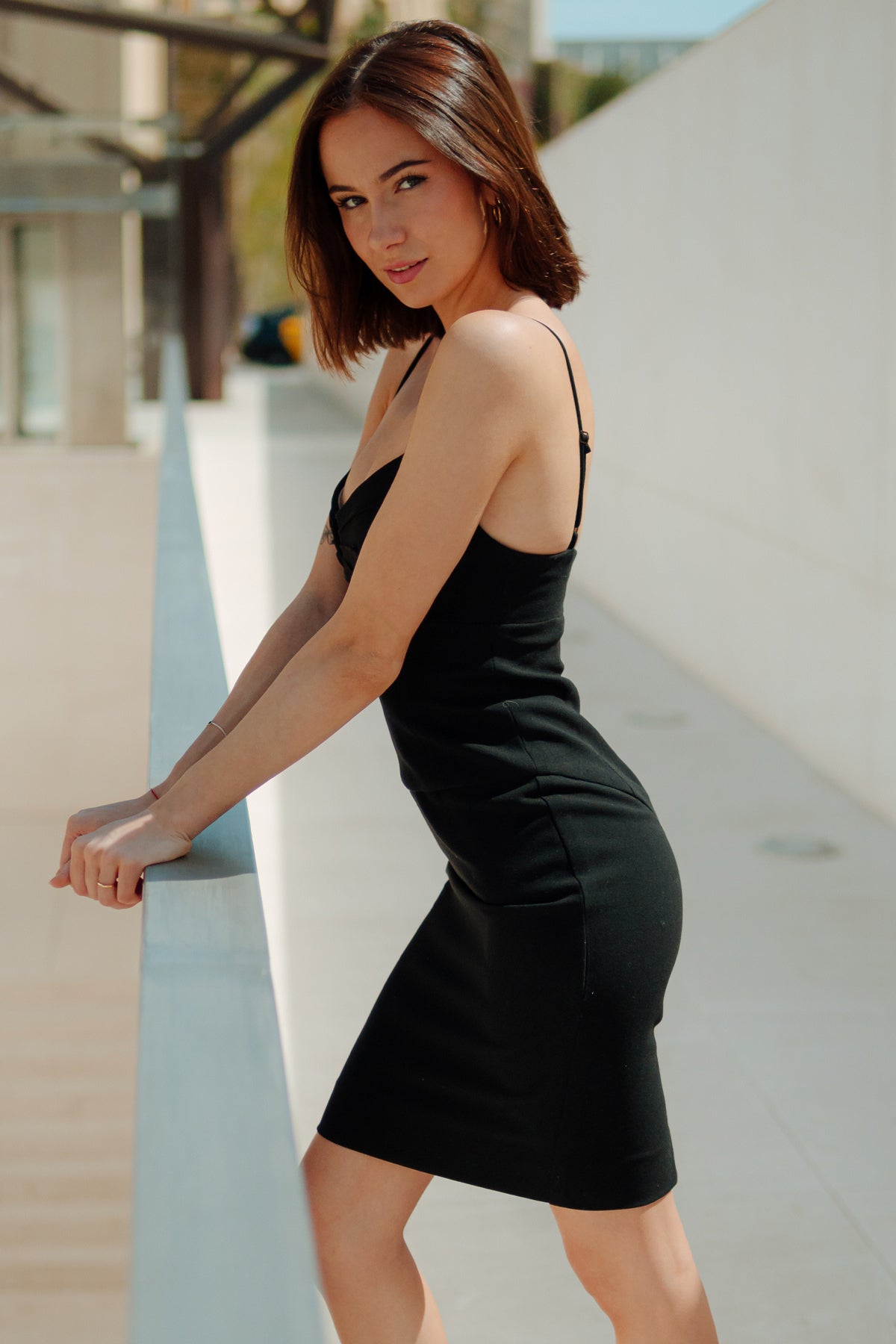 Vista lateral del vestido corto Black Halo en negro, mostrando su silueta estructurada y caída elegante, sobre fondo neutro