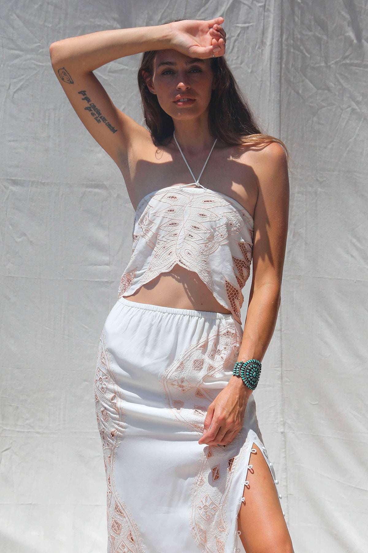 Modelo posando de frente con el crop top Dolly tono Western Bone con mariposa bordada y escote halter bohemio y elegante