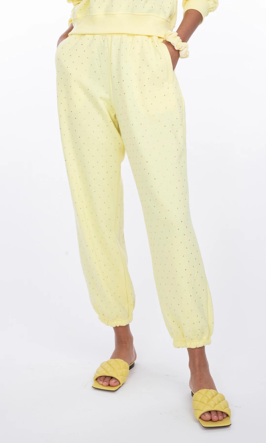 Primer plano de la modelo con Rena Crystal yellow sweatpants con las manos en los bolsillos, reflejando estilo relajado y funcionalidad