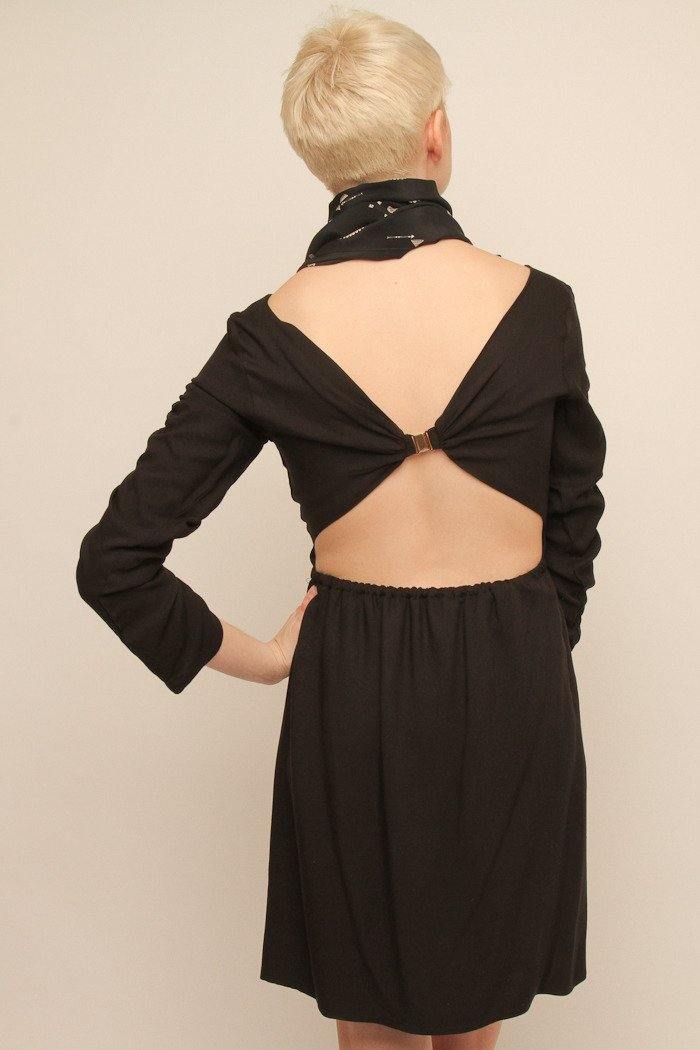 Vista trasera del vestido Eskell Zoma negro con apertura y broche dorado, destacando el detalle abierto de la espalda sobre fondo neutro