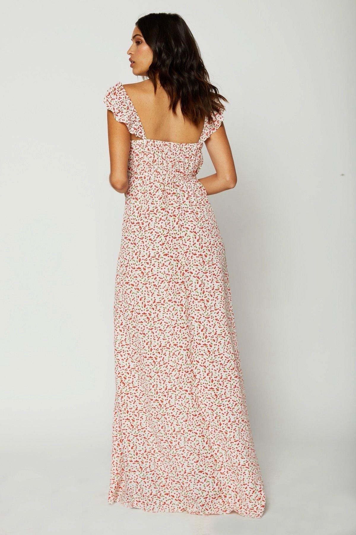 Modelo de espaldas luciendo el vestido Flynn Skye Bardot rosa, tirantes de volantes y espalda descubierta sobre fondo blanco