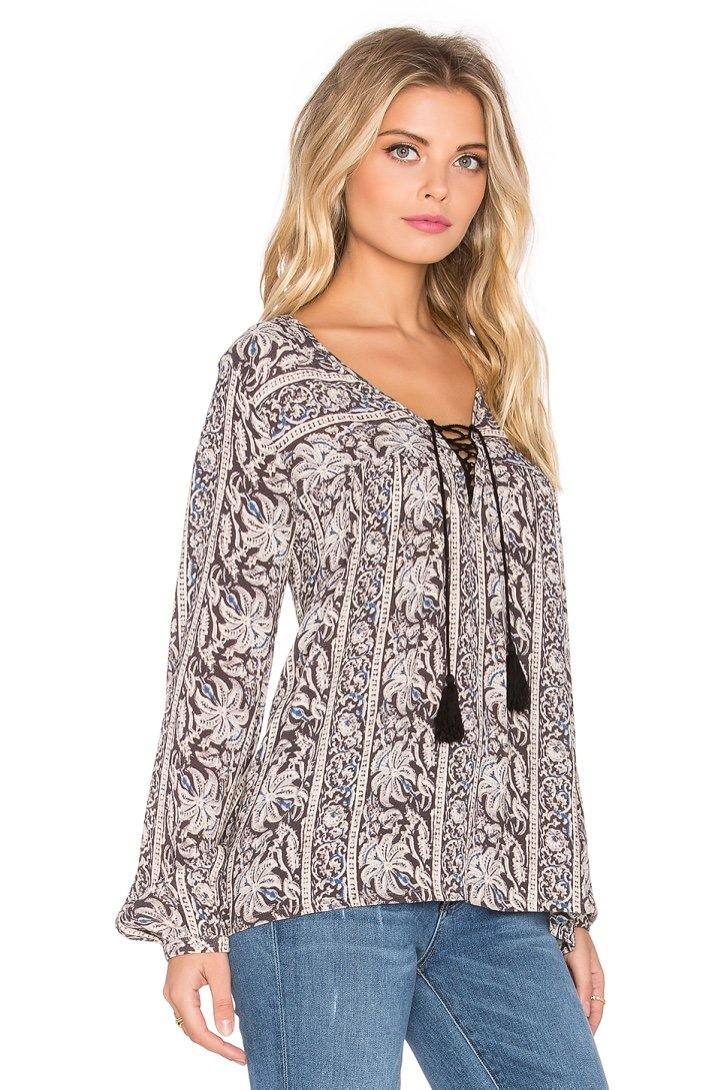 Vista lateral de la blusa negra Sunset Meadow con mangas largas y caída natural, modelo posando en fondo blanco para look sofisticado