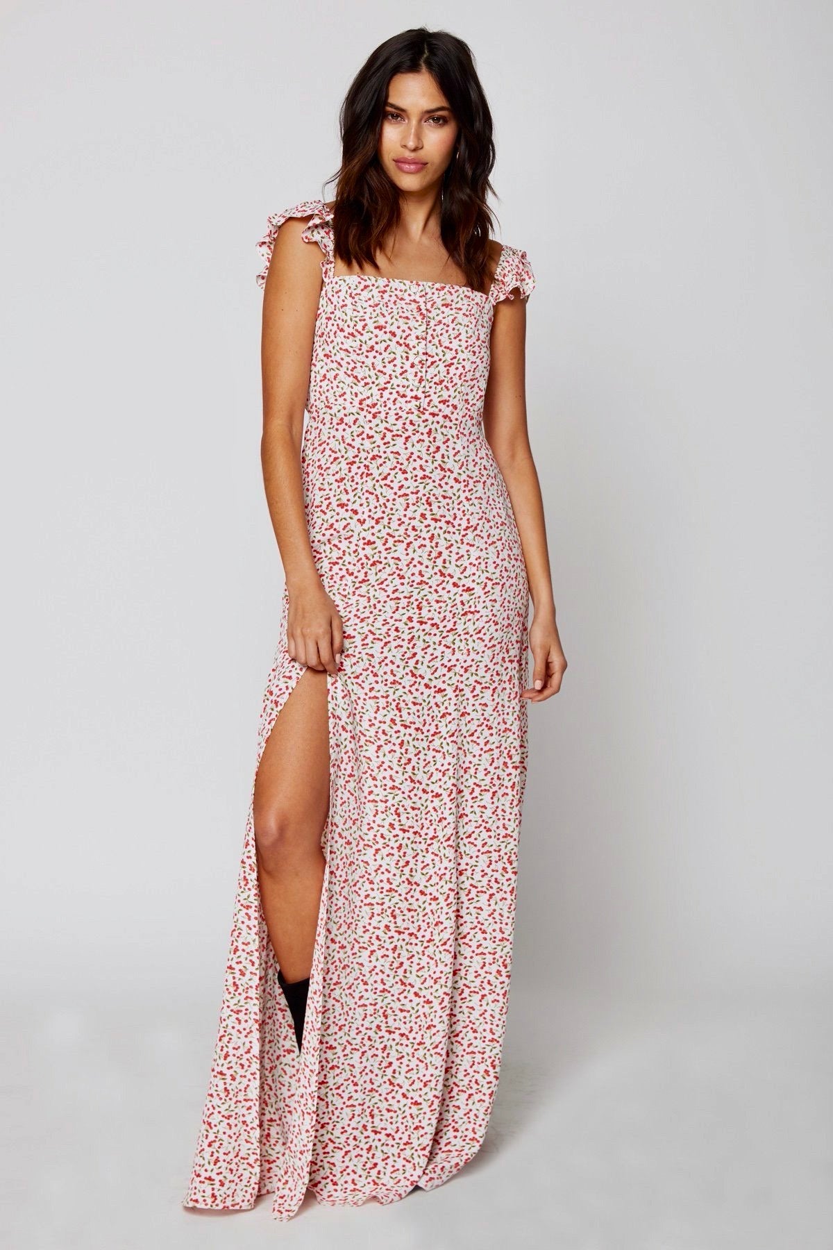 Modelo posando frontalmente con vestido largo Flynn Skye Sweet Cherry Pie en rosa cereza, volantes en hombros y abertura lateral sobre fondo blanco