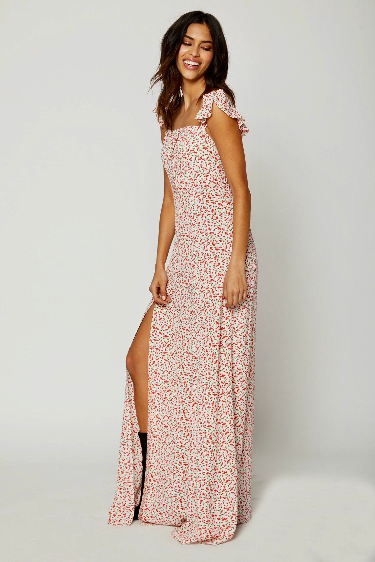 Vista lateral del vestido Bardot Sweet Cherry Pie, mostrando silueta femenina y abertura en muslo, con caída fluida sobre fondo blanco