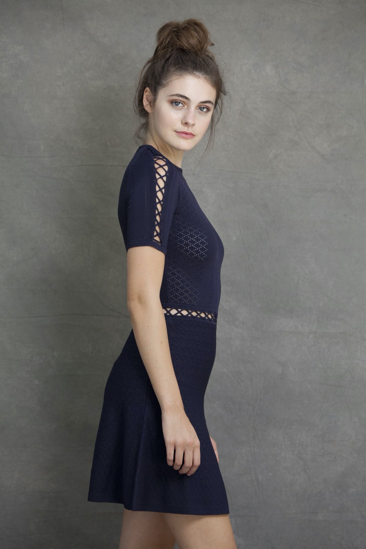 Modelo en vista lateral con vestido Alexa Fit and Flare azul navy resaltando silueta femenina y movimiento de la falda