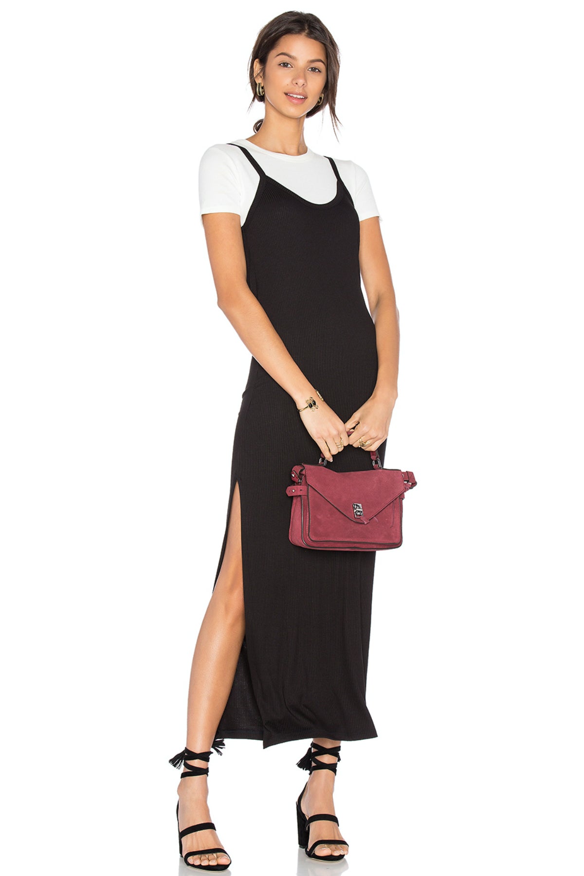 Modelo posando con el vestido largo Caleigh & Clover en terciopelo negro, con camiseta blanca debajo, tirantes finos y abertura lateral, sobre fondo neutro