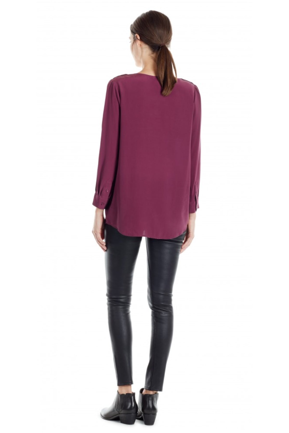 La modelo muestra la parte trasera de la blusa Joie Marlo Shiraz en fondo blanco, resaltando costura central y estilo minimalista