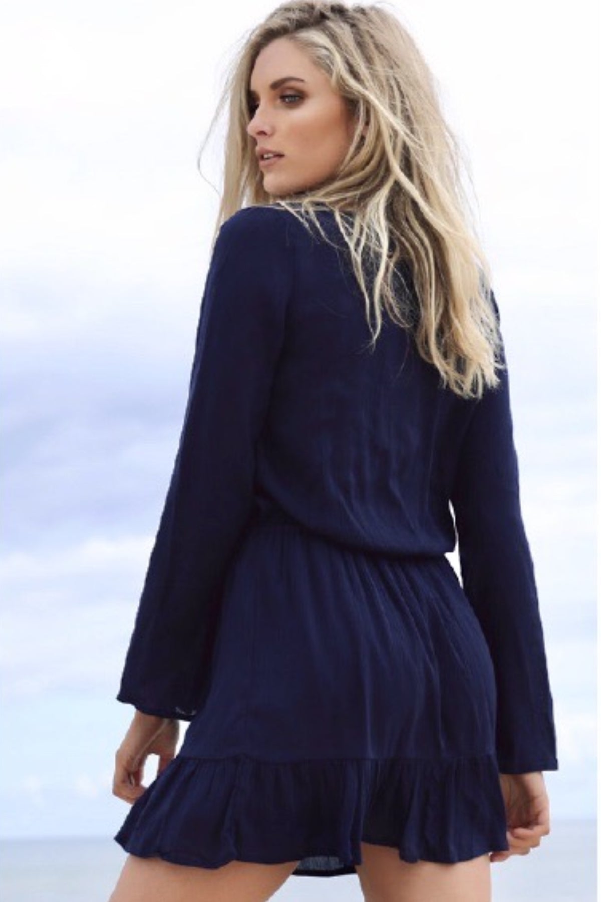 Modelo de espaldas con vestido corto Wilde Heart de manga larga en color navy, mostrando el diseño ajustado y elegante del respaldo sin costuras visibles