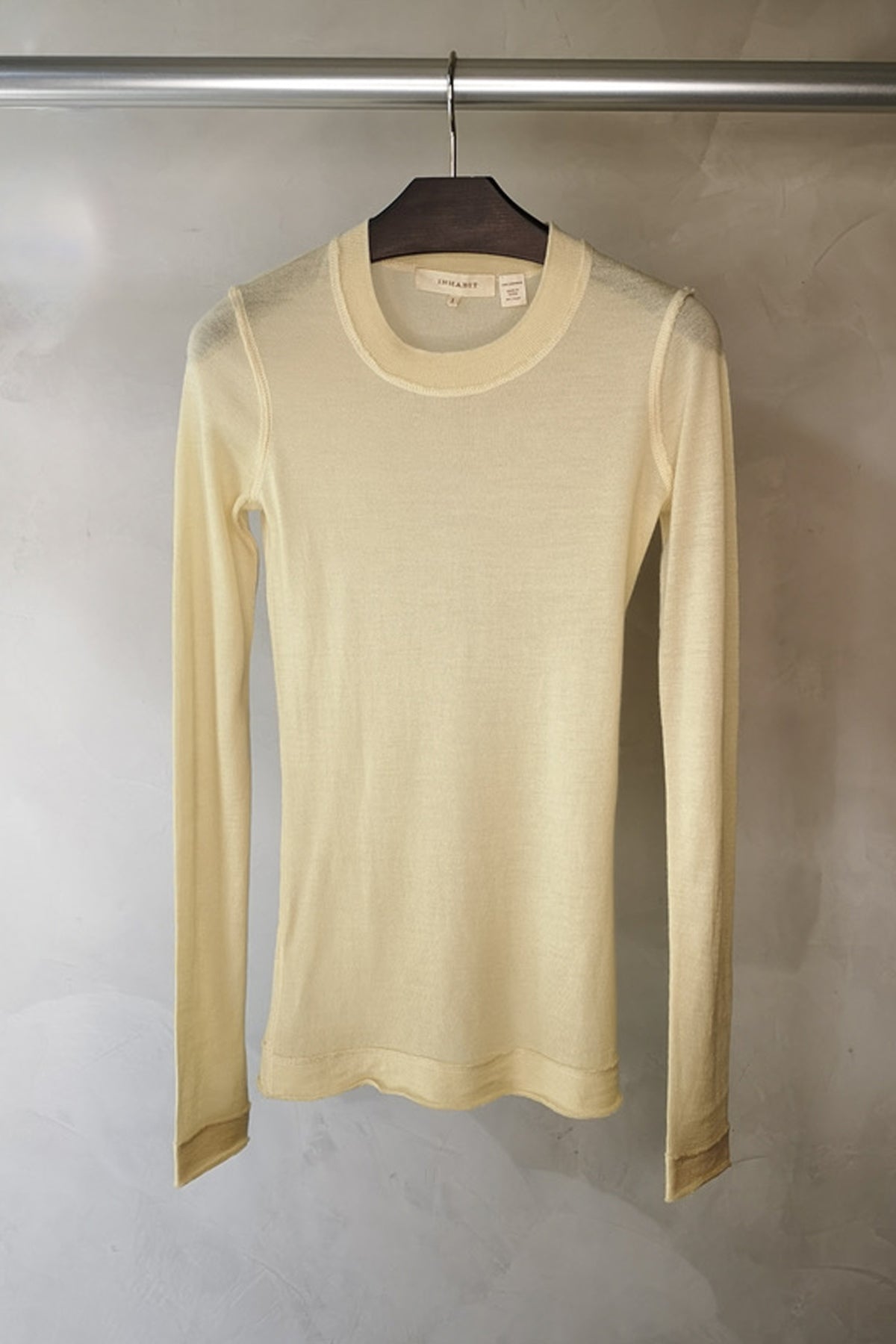 Jersey Inhabit cuello redondo color amarillo pastel sobre fondo neutro, tejido premium de cachemira, mangas largas y diseño atemporal para looks sofisticados