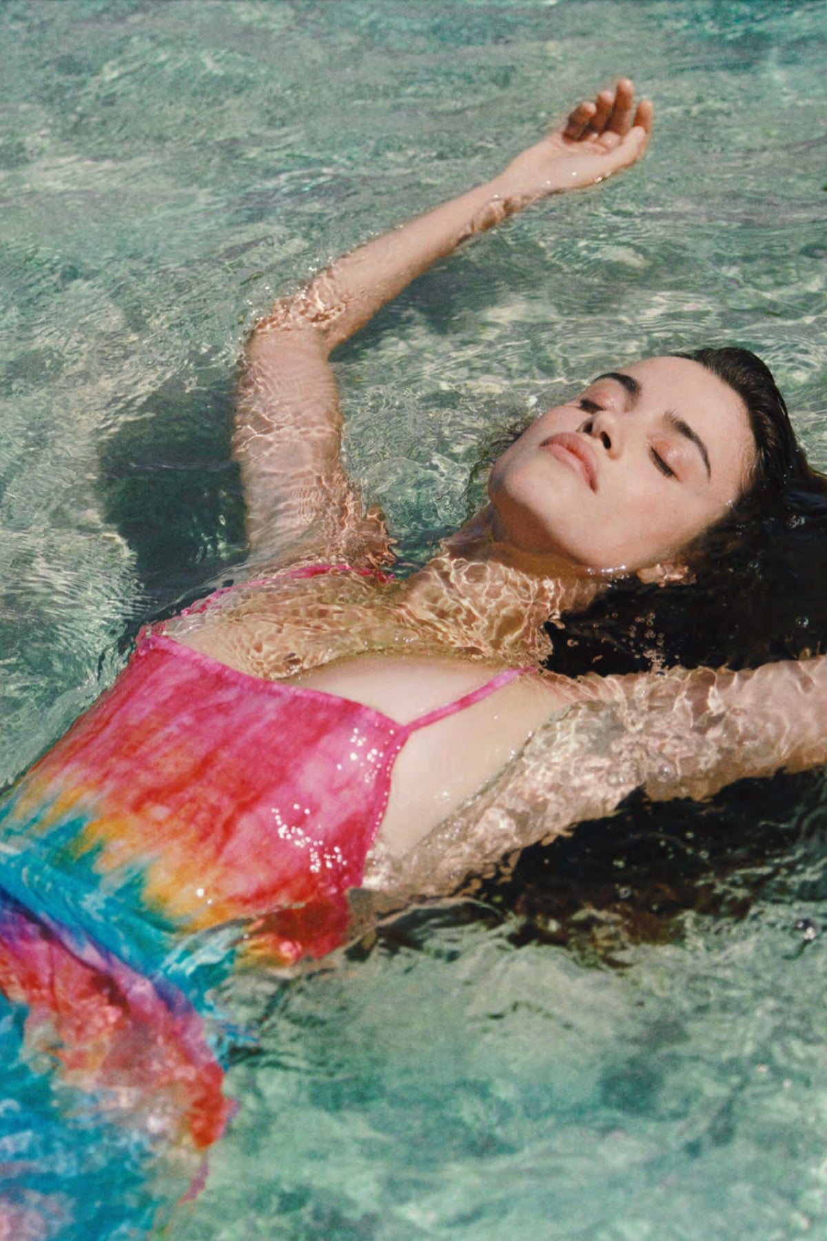 Modelo tumbada en el agua de la playa luciendo el vestido maxi Flynn de Tiare Hawaii con estampado tie dye y tejidos ligeros