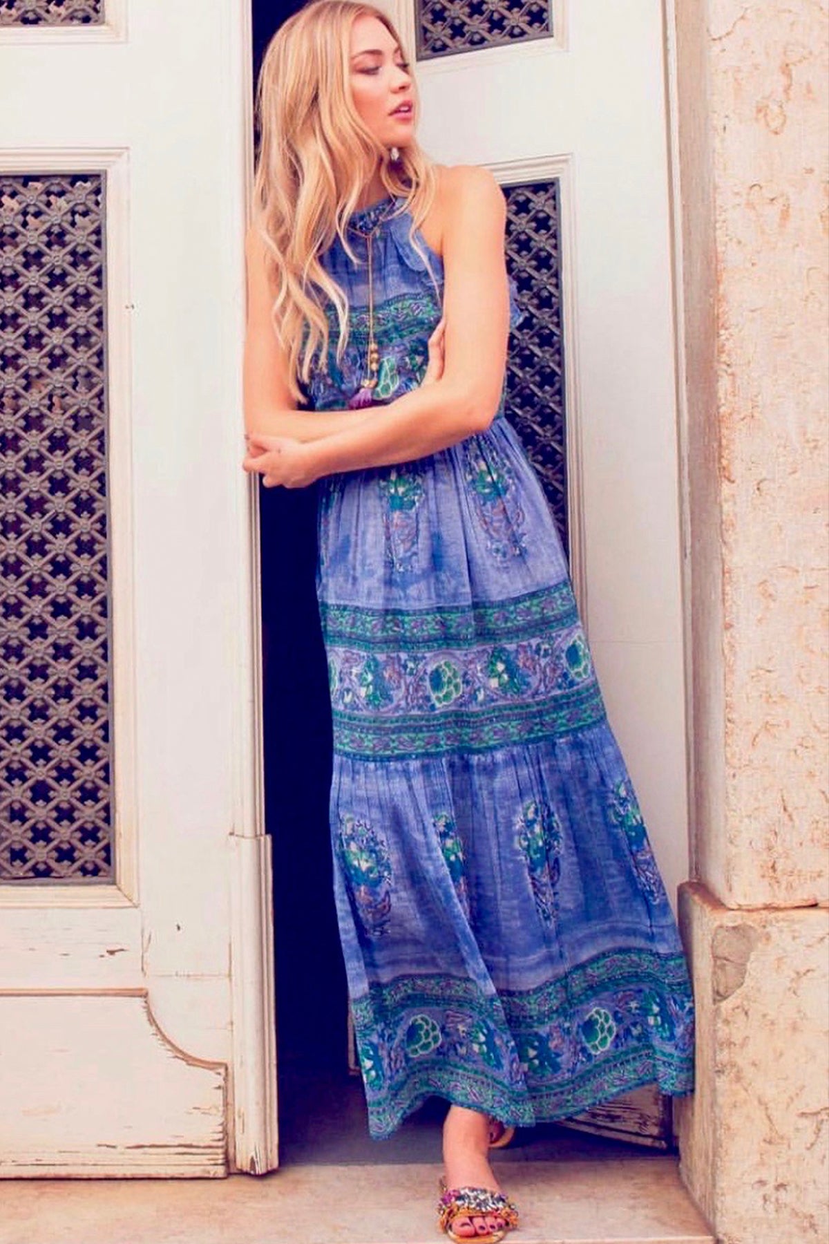 Modelo posando vista frontal con vestido largo Bell azul, volante en sisa y falda fluida, destacando estampado y caída elegante