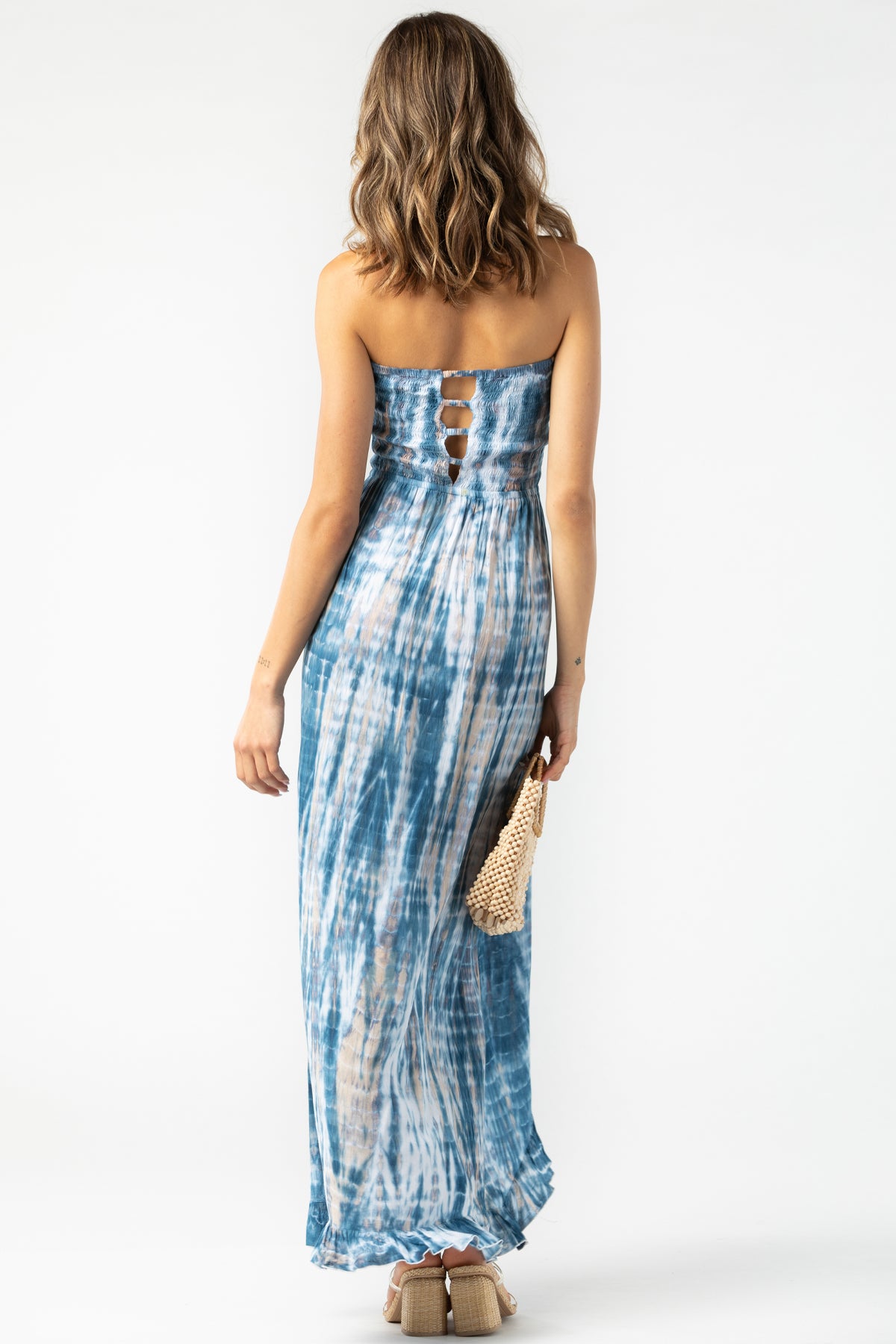 Modelo con Flynn maxi navy‑stone‑white en vista trasera, destacando cut‑out en espalda y falda cruzada para look sofisticado