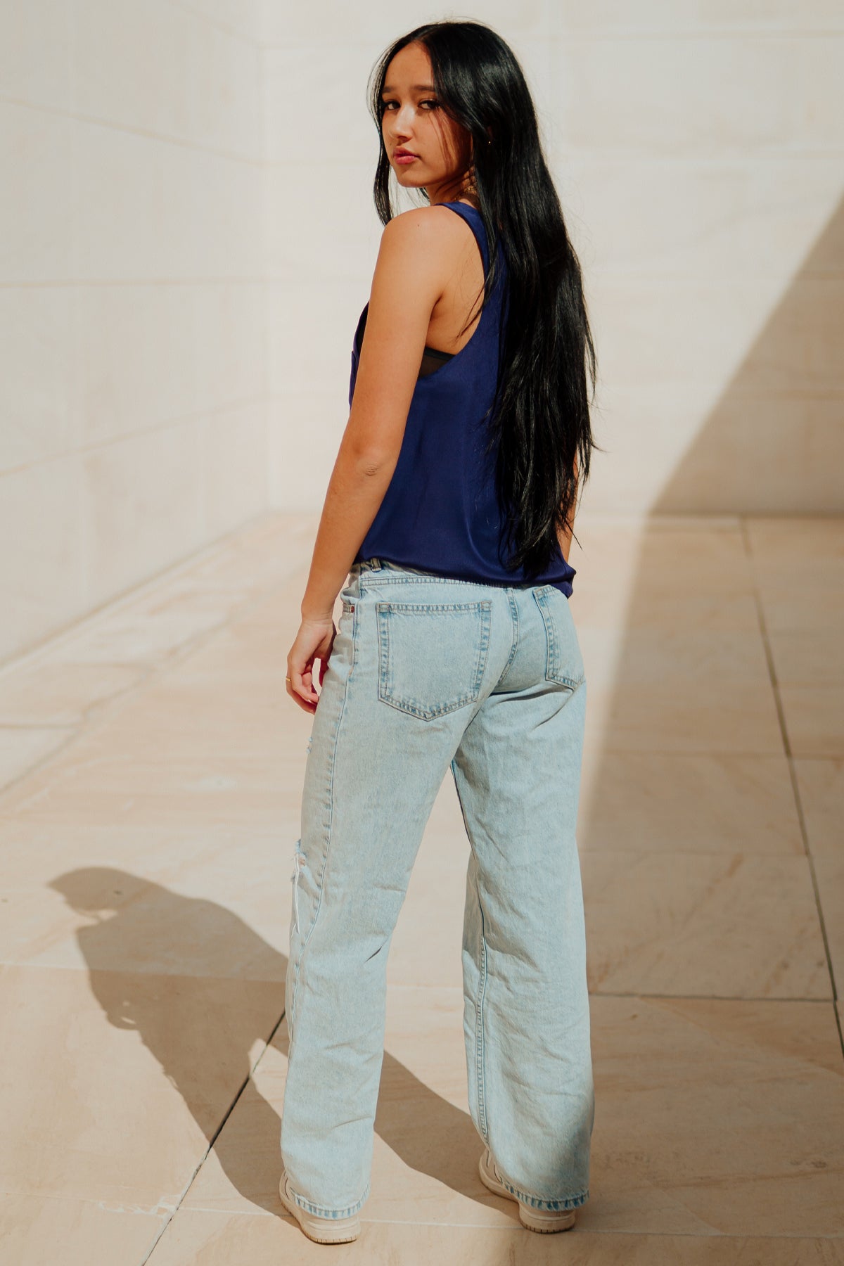 Modelo posando de espaldas con el top Wren de seda, destacando la caída natural y la elegancia de la prenda