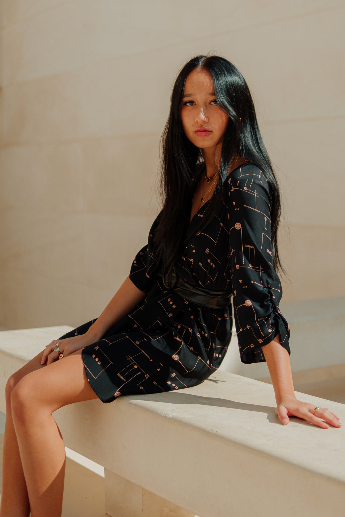 Detalle de la manga ¾ con estampado dorado del vestido Eskell Esme sobre fondo neutro, resaltando su elegancia