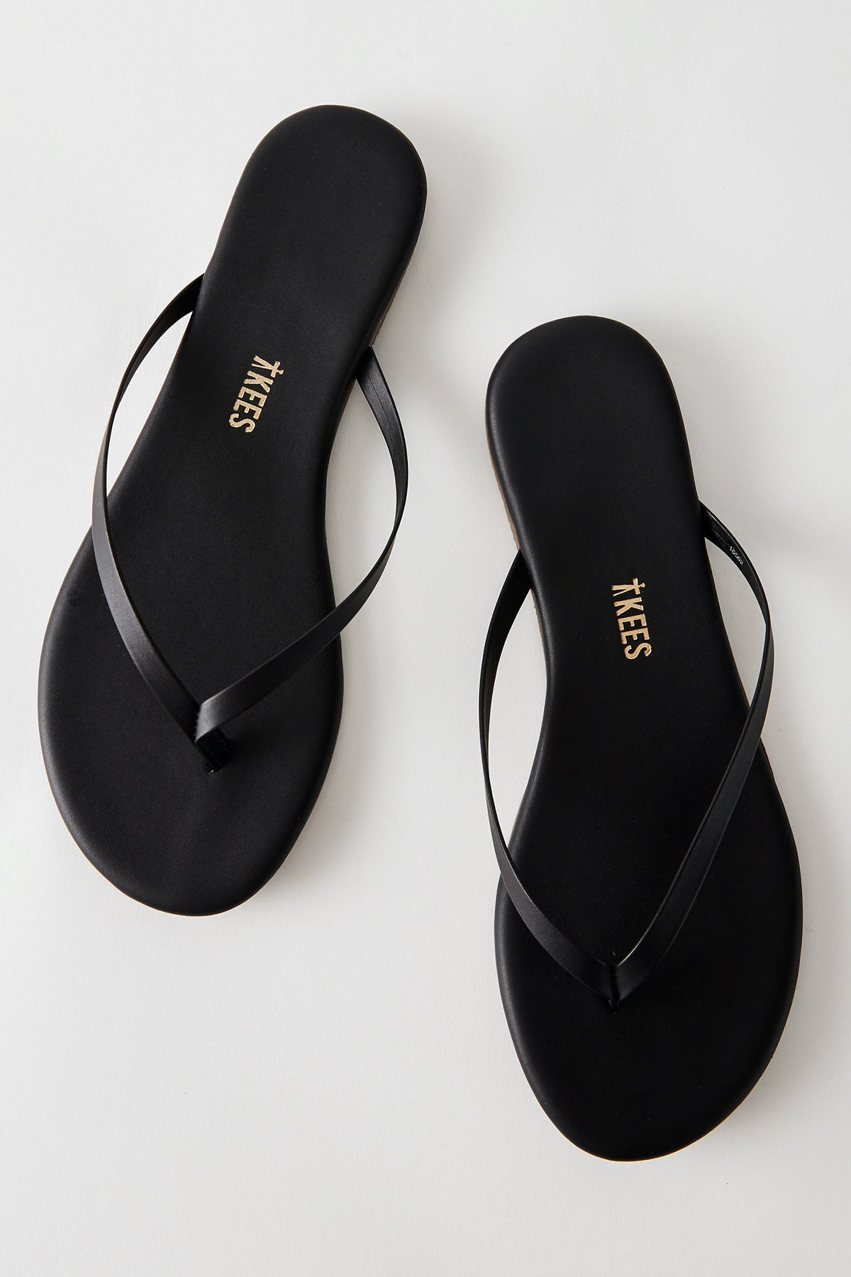 Vista superior de las dos Tkees Black Flip Flops negras, sandalias planas con diseño limpio perfectas para el día a día