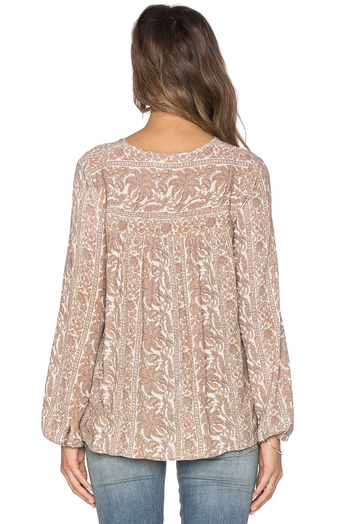 Imagen de modelo posando de espaldas con blusa marrón Sunset Meadow, mostrando diseño sencillo y escote con lazo en fondo blanco