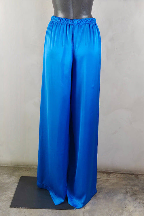 Parte trasera de pantalones de seda azul en maniquí, con textura brillante y corte cómodo ideal para looks elegantes y frescos