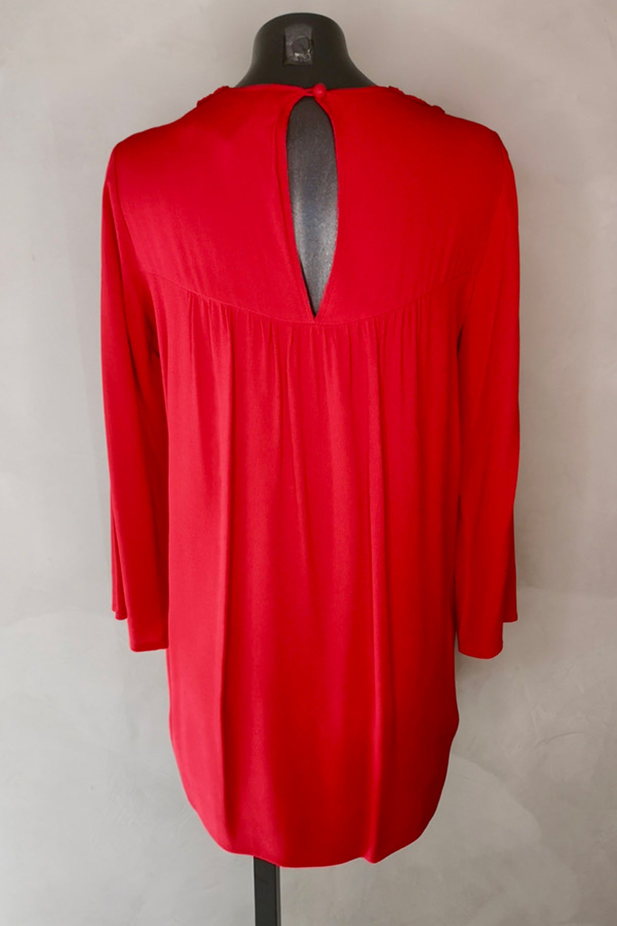 Vista trasera del vestido corto Rosemary en lipstick red, cerrando con ojal y botón ojo de cerradura, sobre fondo neutro