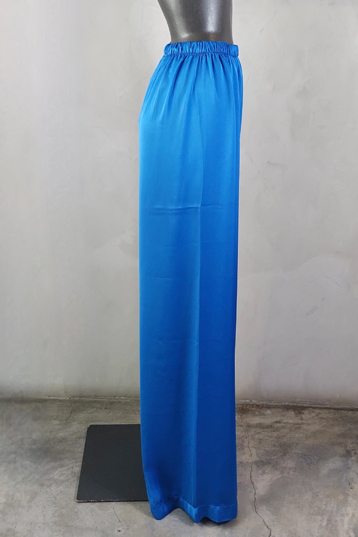 Perfil lateral de pantalones de seda azul con caída ligera y corte fluido que realza la silueta femenina con elegancia natural