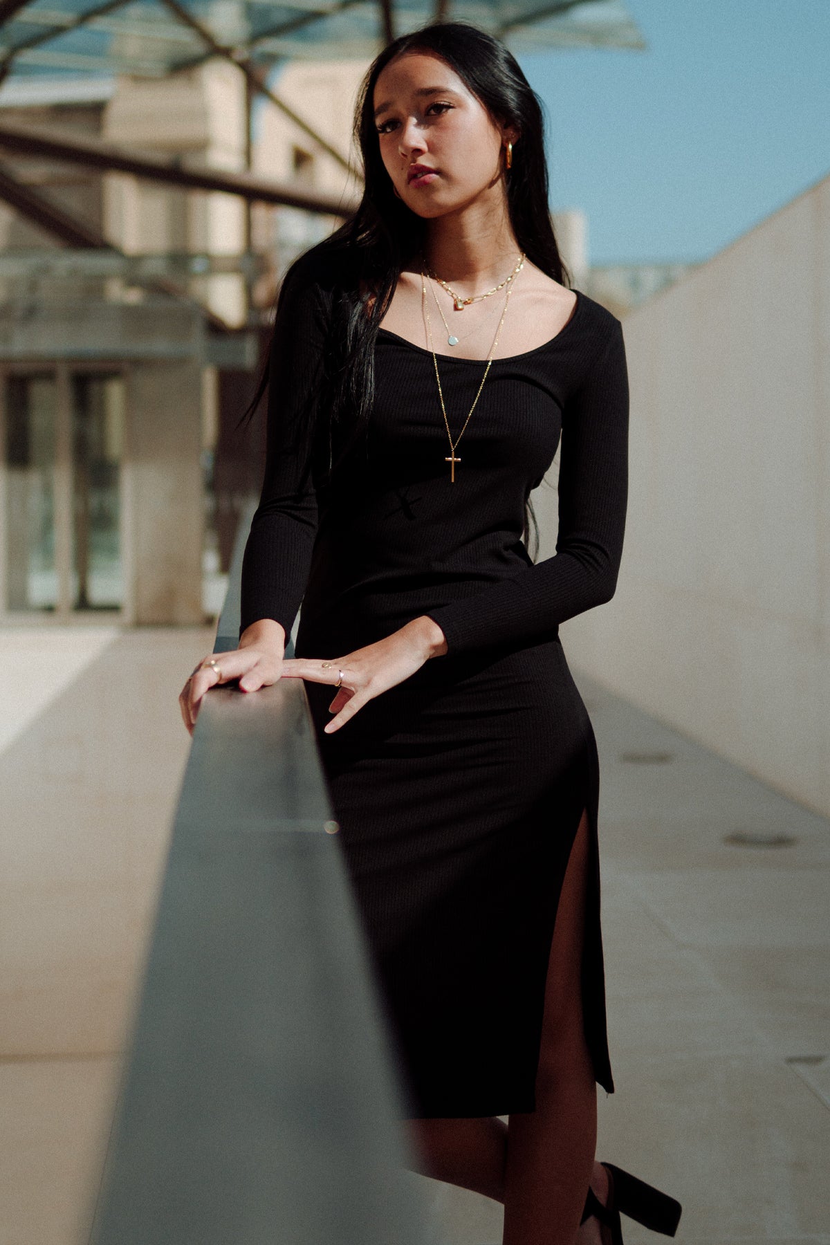 Modelo posando frontalmente apoyada con vestido Vila negro, mostrando elegancia y textura ajustada del vestido