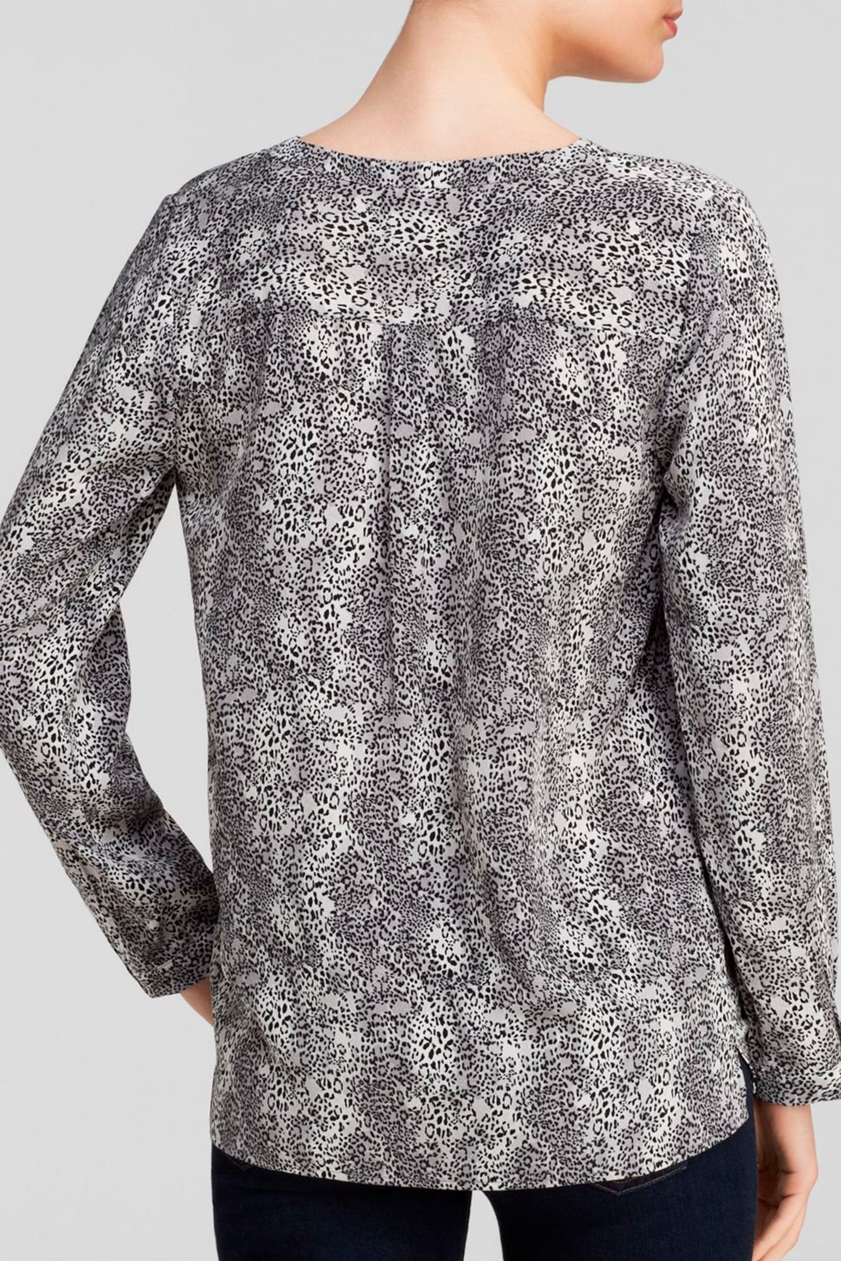 Detalle del estampado cheetah en negro sobre la seda blanca de la blusa Joie Michi, realzando textura y diseño sofisticado