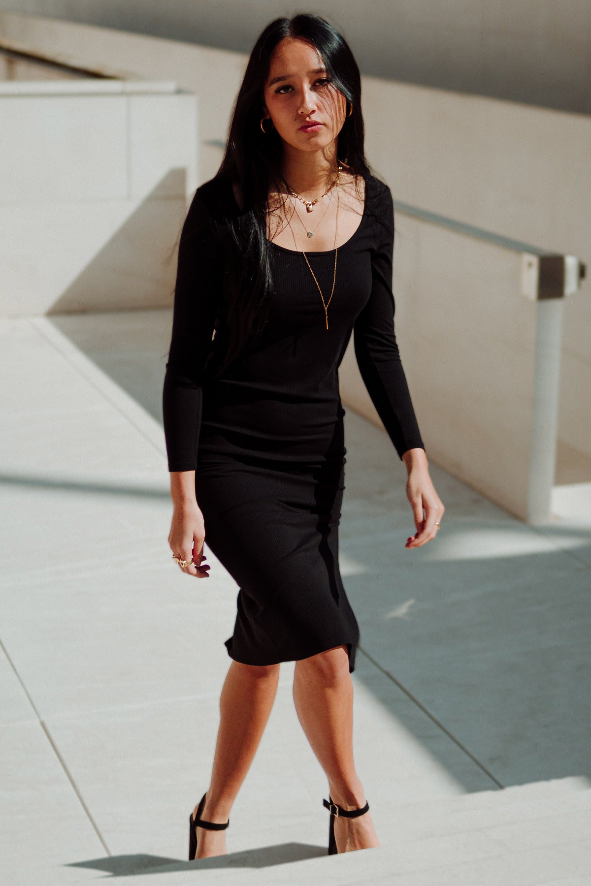 Modelo en vista frontal con vestido midi Vila negro, resaltando el diseño elegante y acabado ajustado al cuerpo