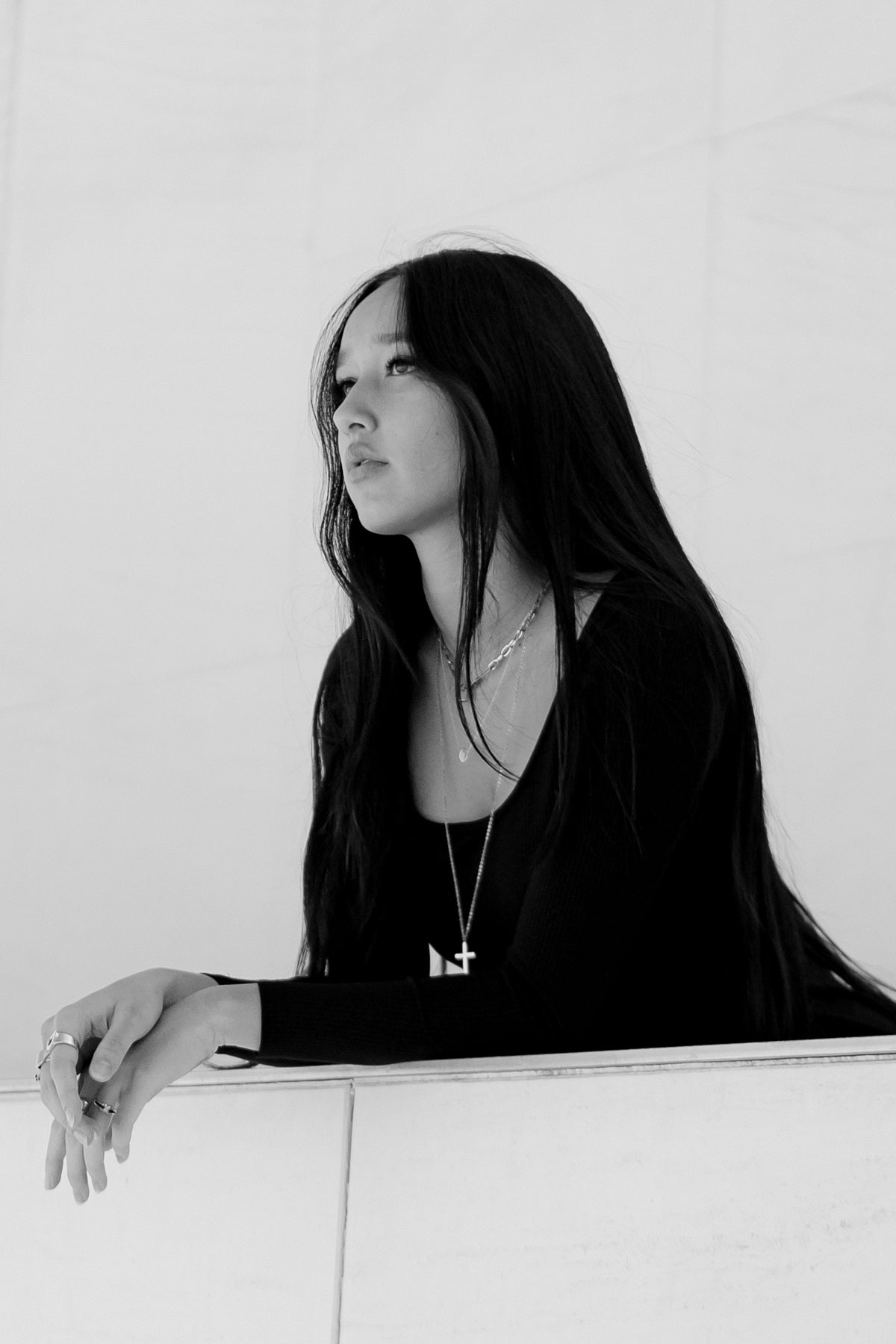 Modelo apoyada en muro con vestido midi negro Vila en blanco y negro, proyectando estilo y elegancia urbana