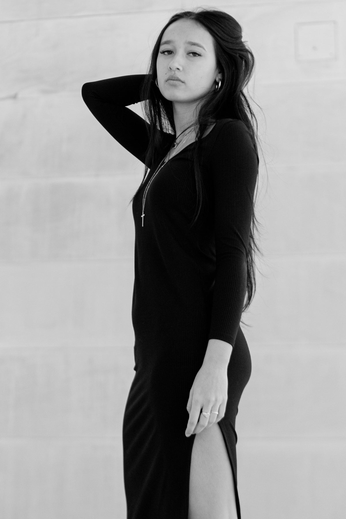 Modelo posando lateralmente con vestido negro Vila, mostrando detalles del canalé y corte midi en blanco y negro