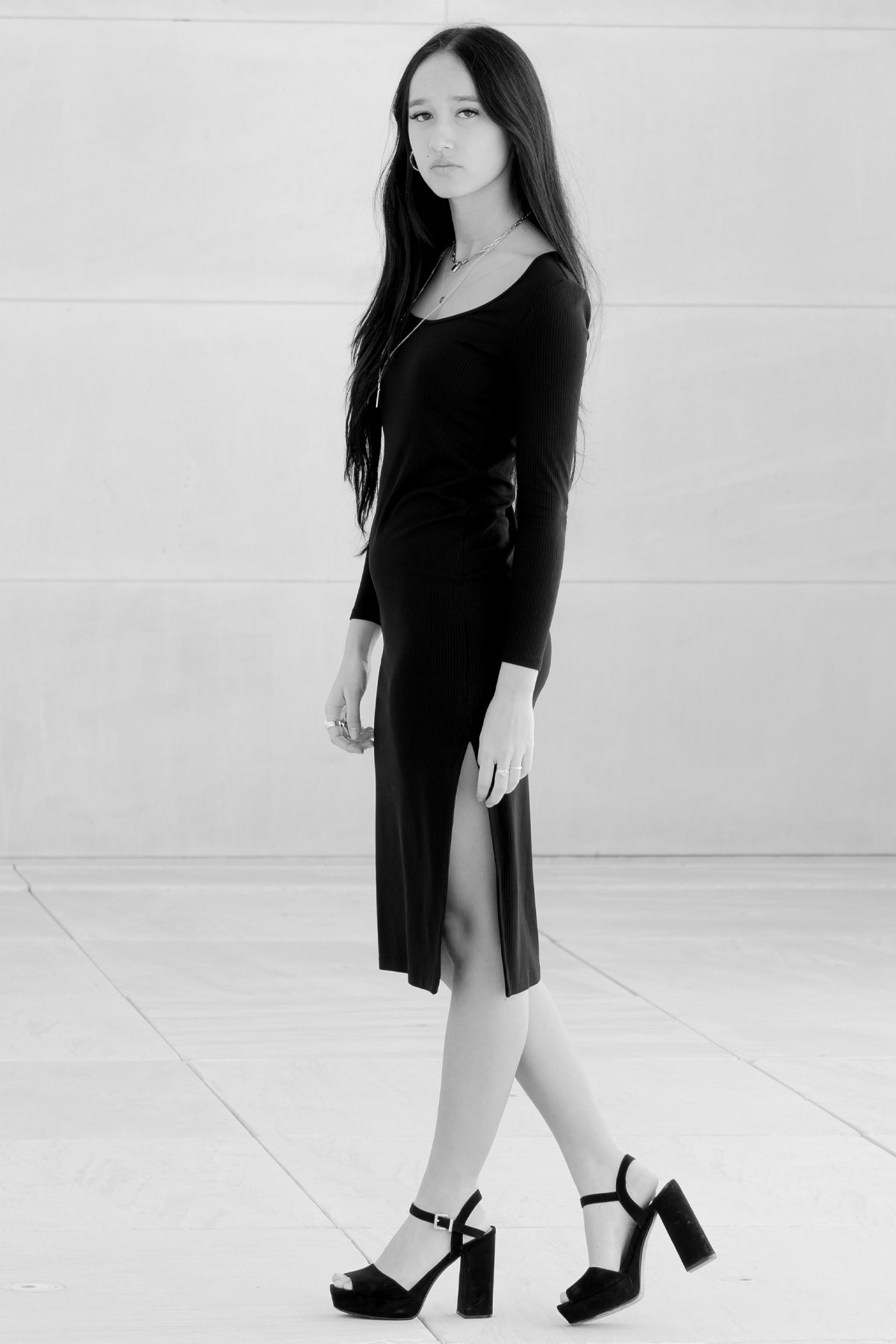 Modelo de perfil en foto blanco y negro con vestido negro Vila, destacando silueta y textura canalé