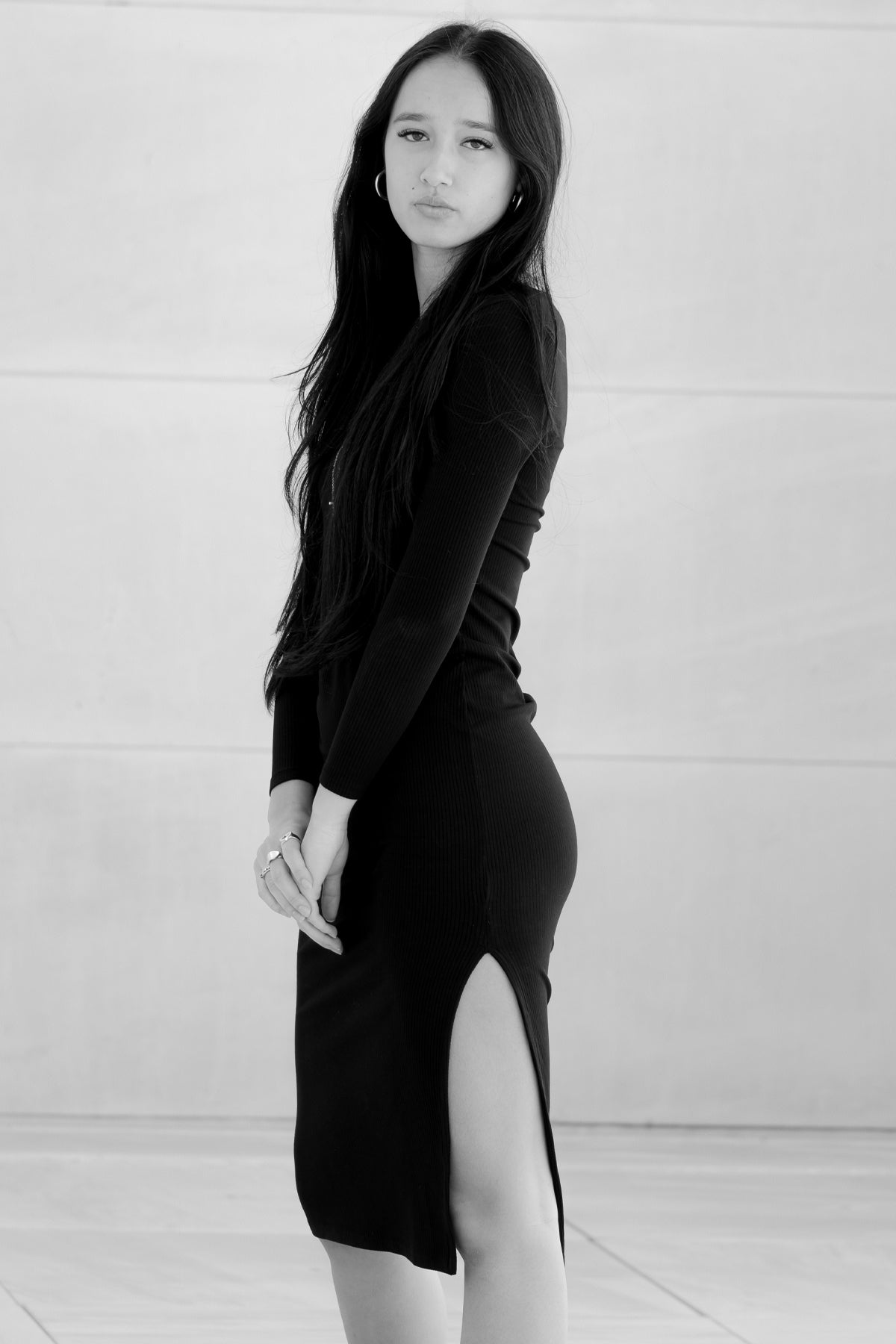 Modelo posando de perfil en blanco y negro con vestido midi Vila rojo, resaltando la silueta y textura elegante