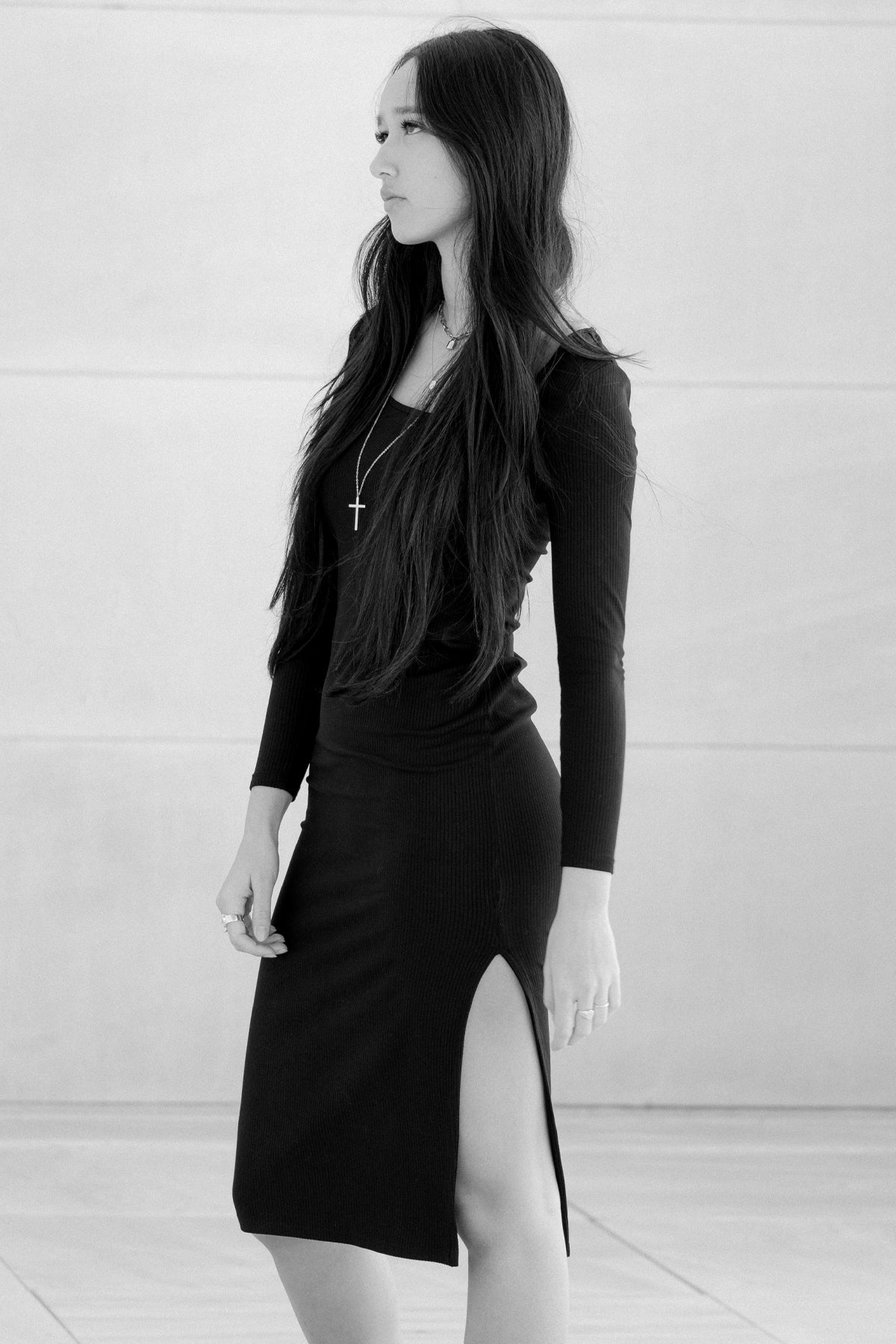 Modelo posando de perfil en blanco y negro con vestido midi Vila negro, enfatizando líneas y textura del vestido