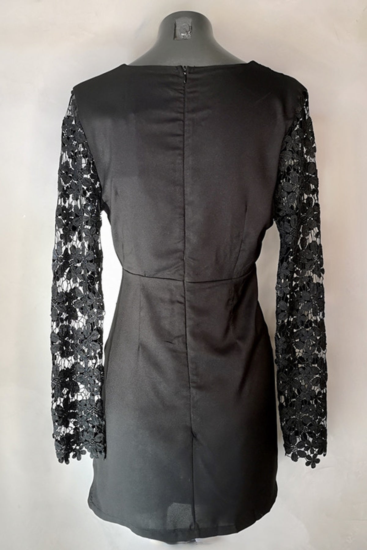 Vista trasera del Reverse Lace Mini Dress negro en maniquí destacando su diseño sin forro y caída elegante