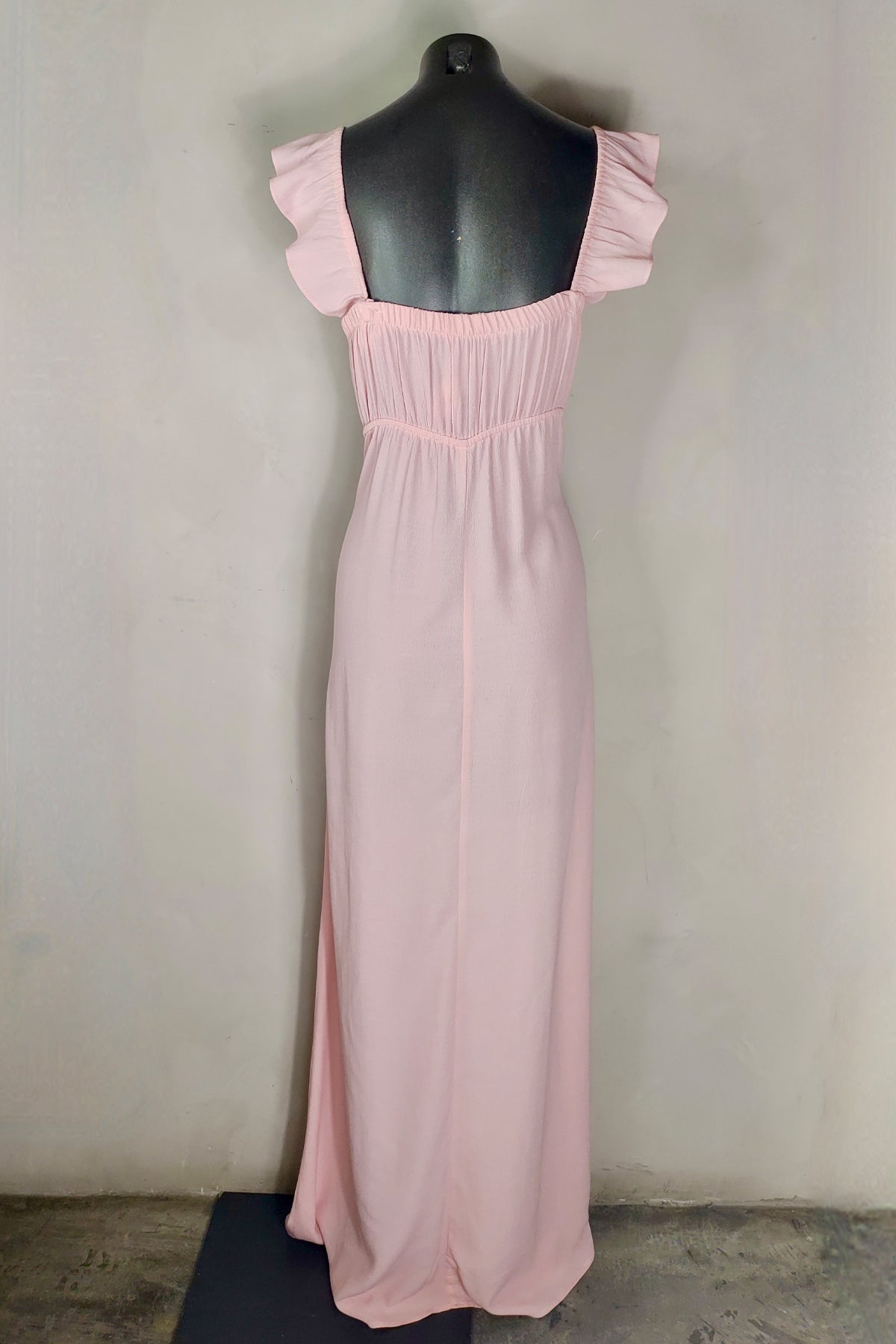 Vista trasera del vestido largo Bardot en maniquí, mostrando espalda descubierta y tirantes de volantes