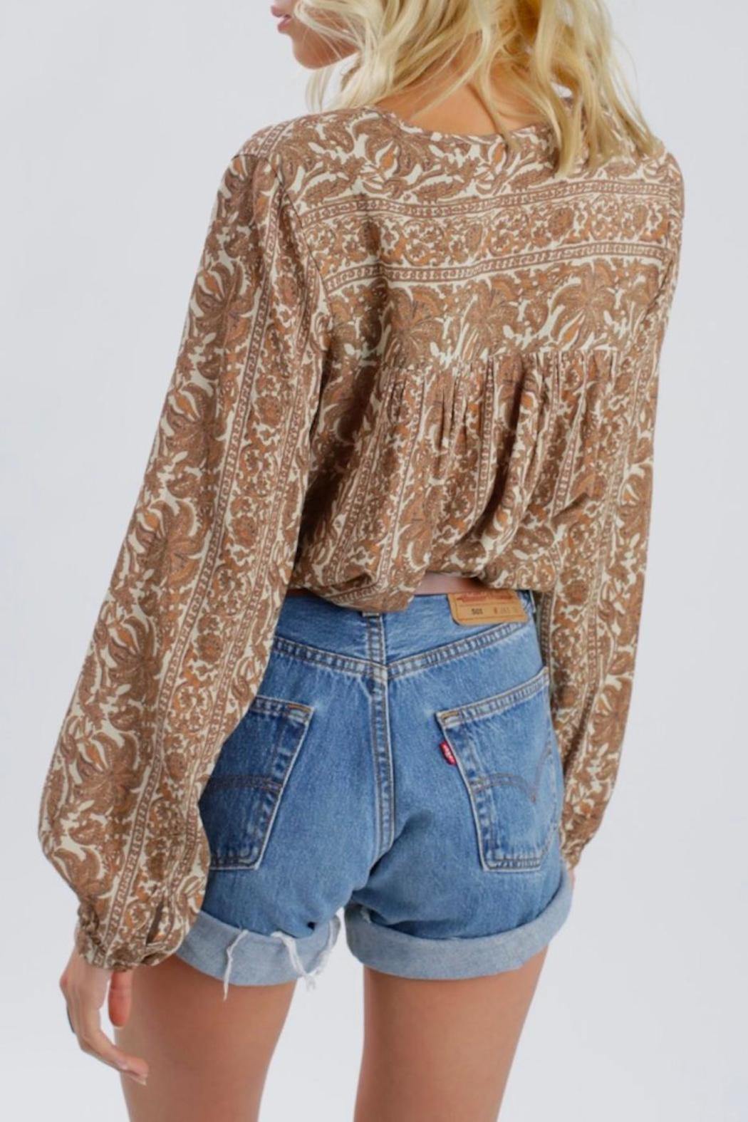 Vista trasera de la blusa marrón Sunset Meadow en modelo, con detalles de costuras y acabado pulido sobre fondo blanco claro