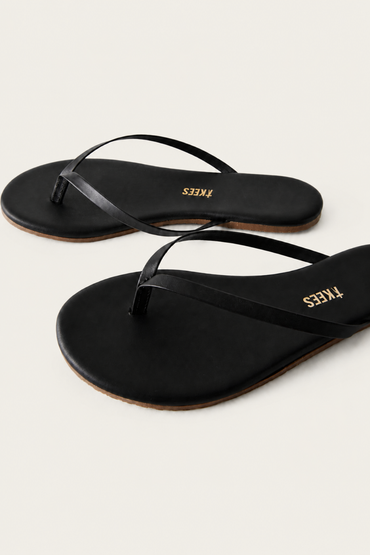 Primer plano de la tira de las Tkees Black Flip Flops en negro, fabricadas con materiales duraderos y resistentes al desgaste