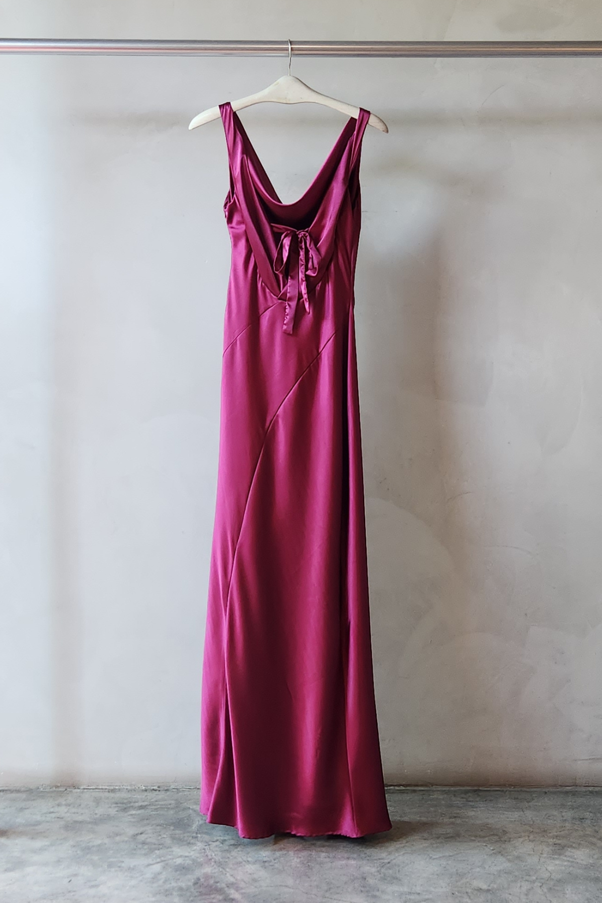 Vista trasera Vestido largo Alfina Granate en raso drapeado con cuello redondo, espalda con lazo, abertura lateral y caída fluida elegante